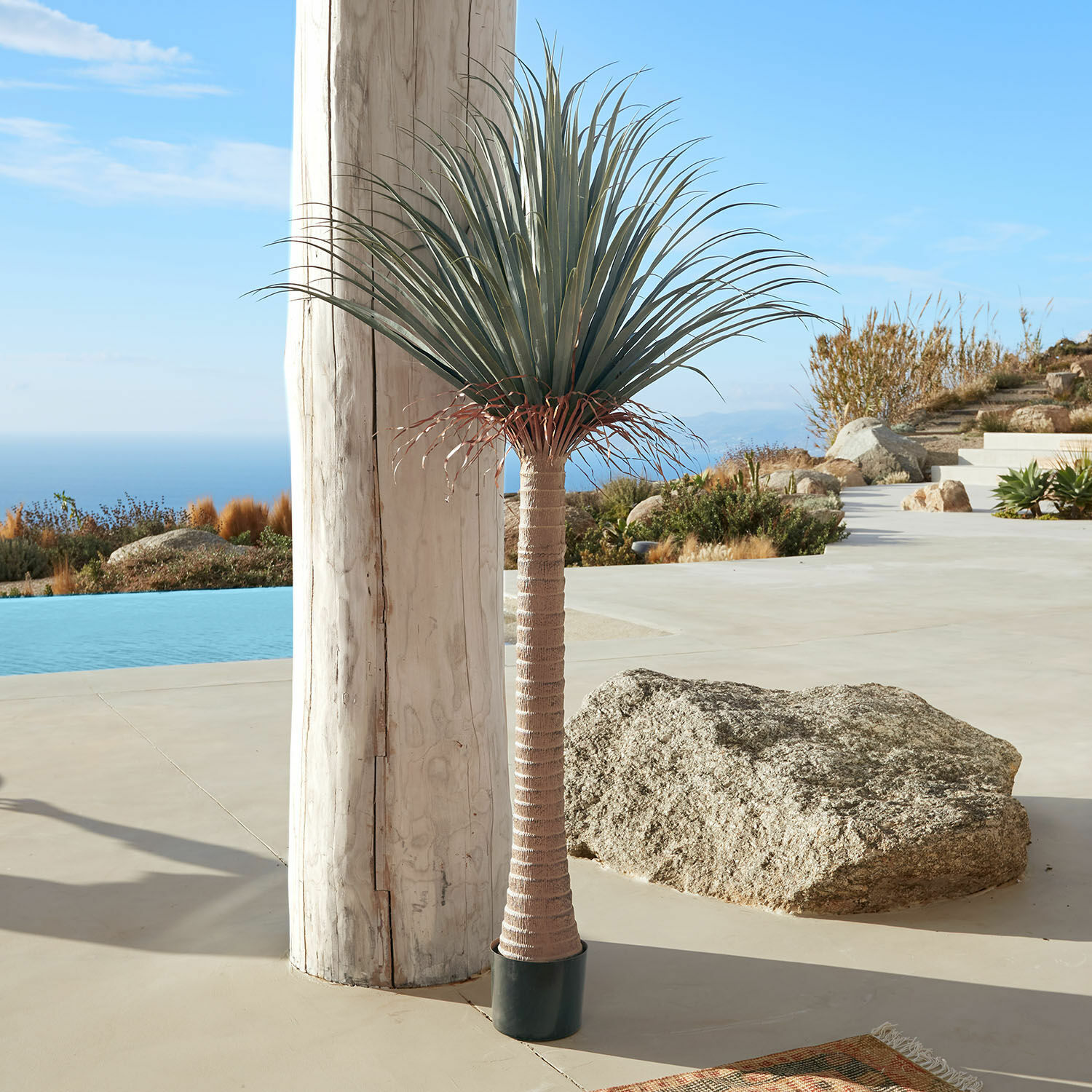 Palmera decorativa Remivon Palma artificial en maceta con tronco marrón y hojas verdes en terraza con vista al mar