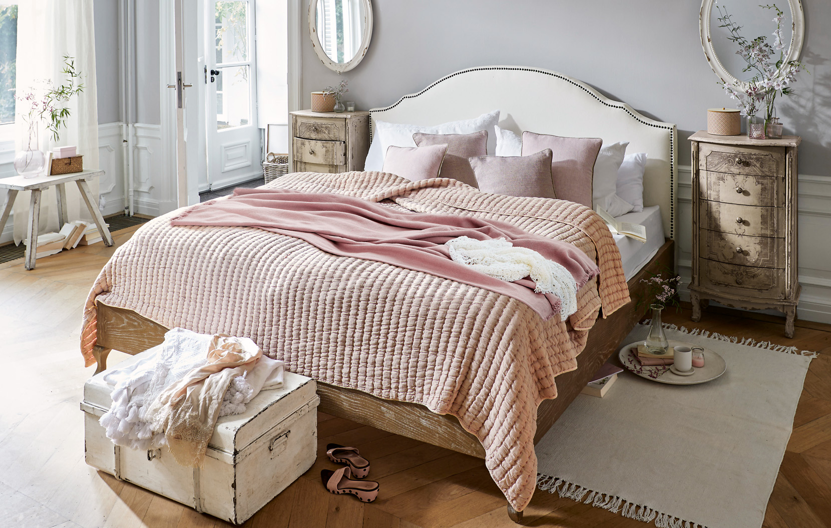 Dormitorio acogedor shabby chic con colcha rosa y muebles de madera vintage para ambiente cálido