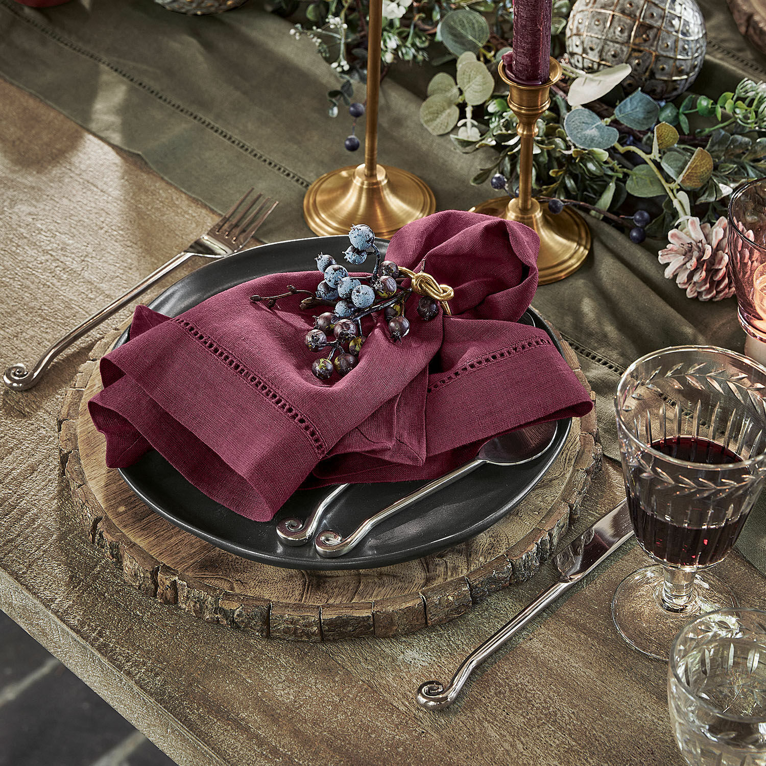 Set de 4 servilletas Covent Garden Base rústica de madera con plato negro y servilleta de lino burdeos sobre mesa de madera