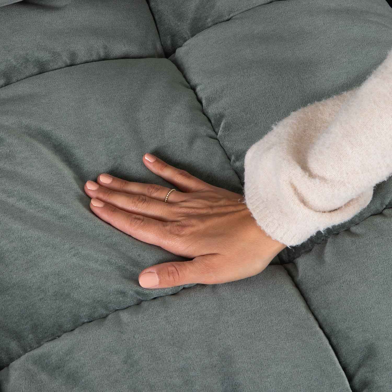 Mano sobre tela acolchada verde suave, destacando la comodidad y calidad del textil