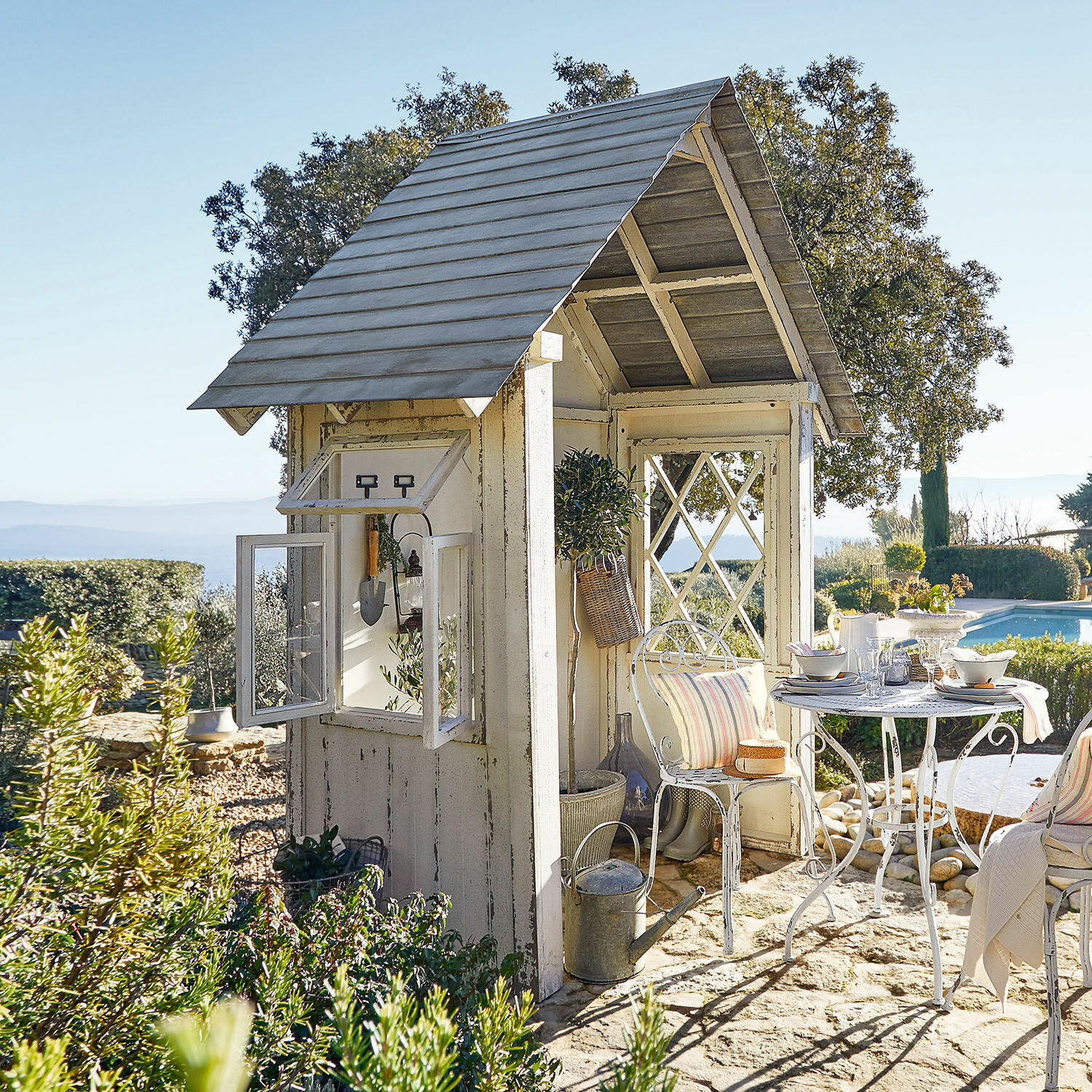 Cobertizo de jardín Sumter Pérgola de madera blanca con mesa y sillas de metal sobre suelo de piedra junto a la piscina