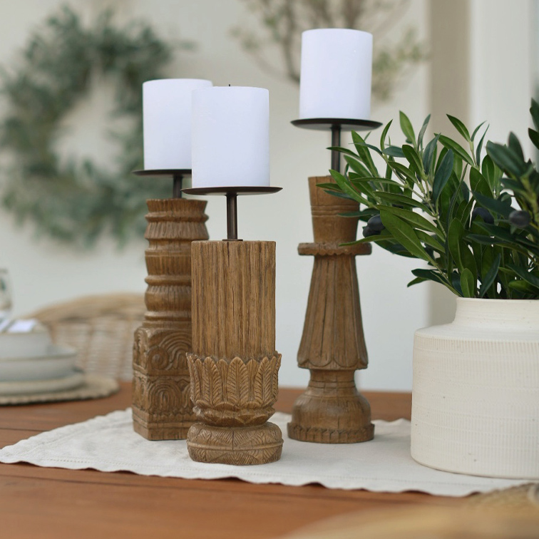 Tres candelabros de madera con velas blancas sobre una mesa, decoración natural para interiores
