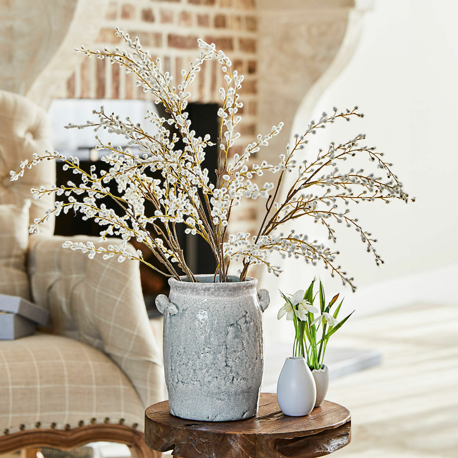 Set de 3 ramas decorativas Palmyra Jarrón de cerámica gris con ramas de amento sobre mesa de madera en sala luminosa