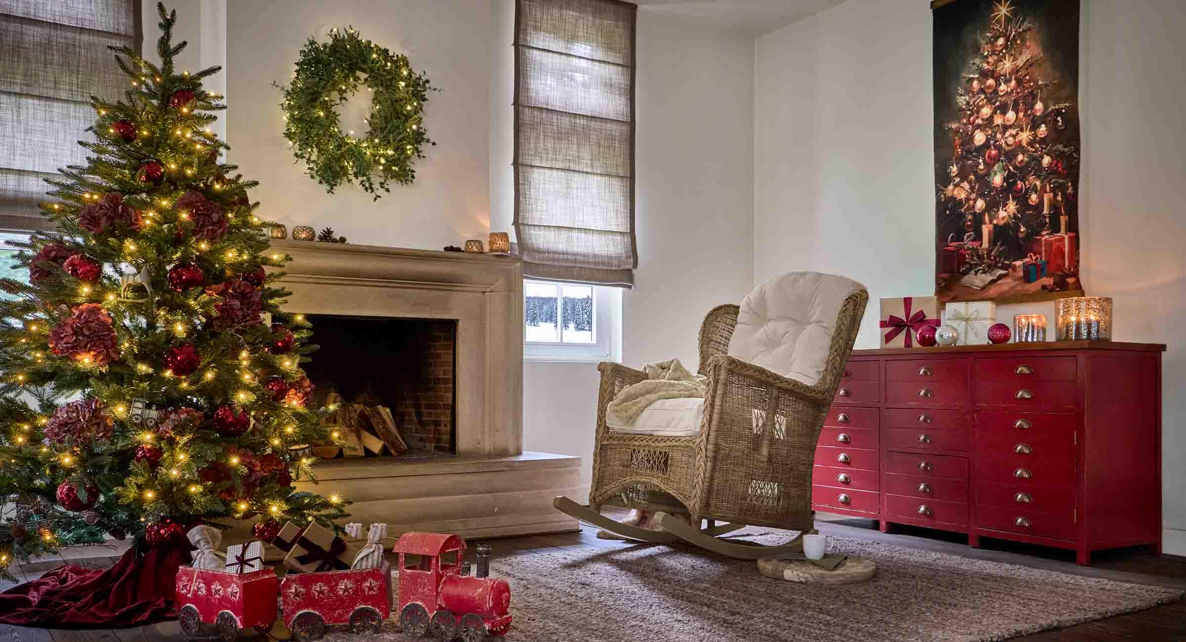 Salón acogedor con árbol de Navidad, mecedora de mimbre y aparador rojo con decoración festiva