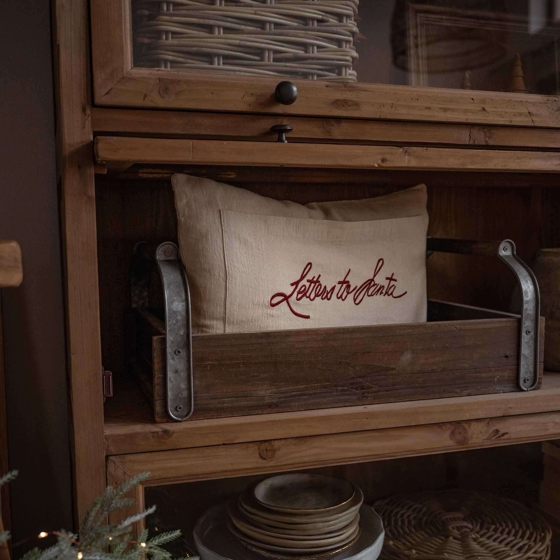 Cojín de lino beige con texto rojo Letters to Santa en caja de madera sobre estante