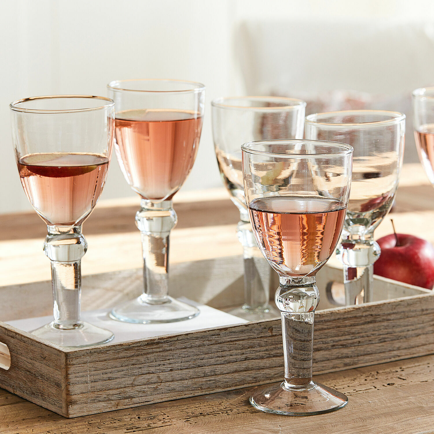 Set de 6 copas de vino Devon Conjunto de vasos transparentes con bebida rosada sobre bandeja de madera, copas de vino