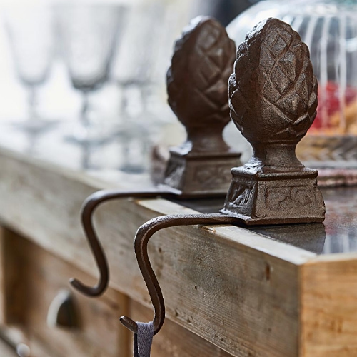 Ganchos decorativos de hierro marrón con diseño de piña sobre encimera de madera
