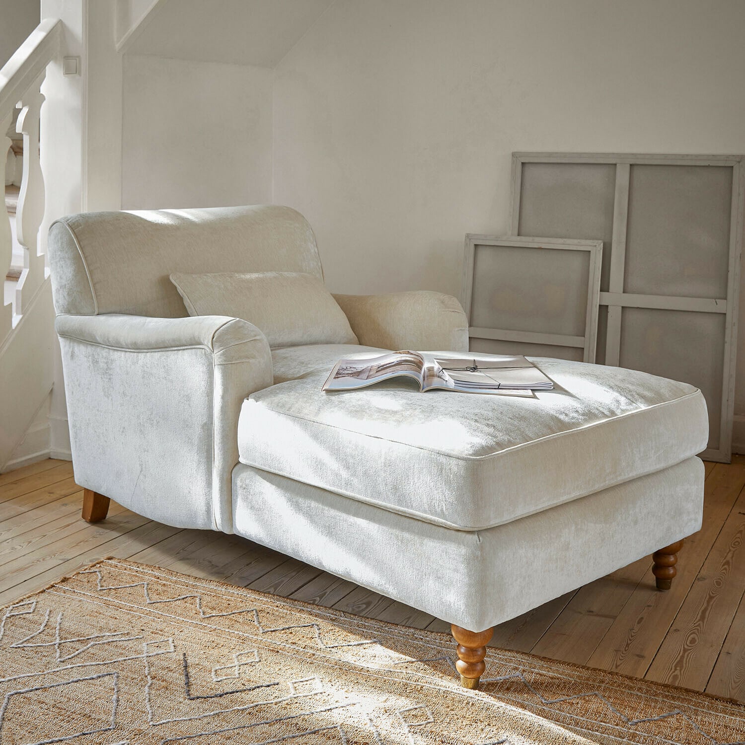 Chaise longue Isa Sillón beige de tela suave con reposapiés y patas de madera en sala luminosa