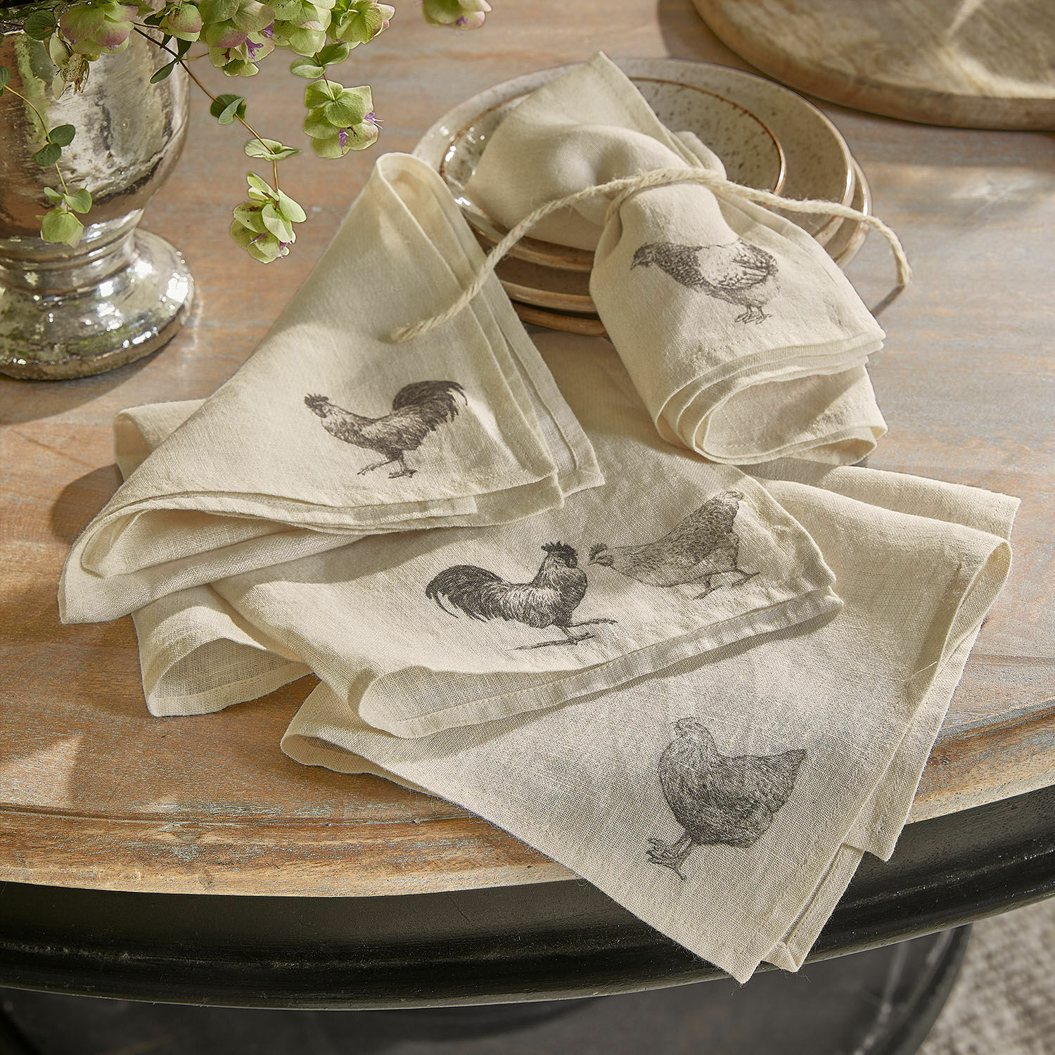 Set de 4 servilletas Walorine Servilletas de lino beige con estampado de gallinas y gallos sobre mesa de madera rústica