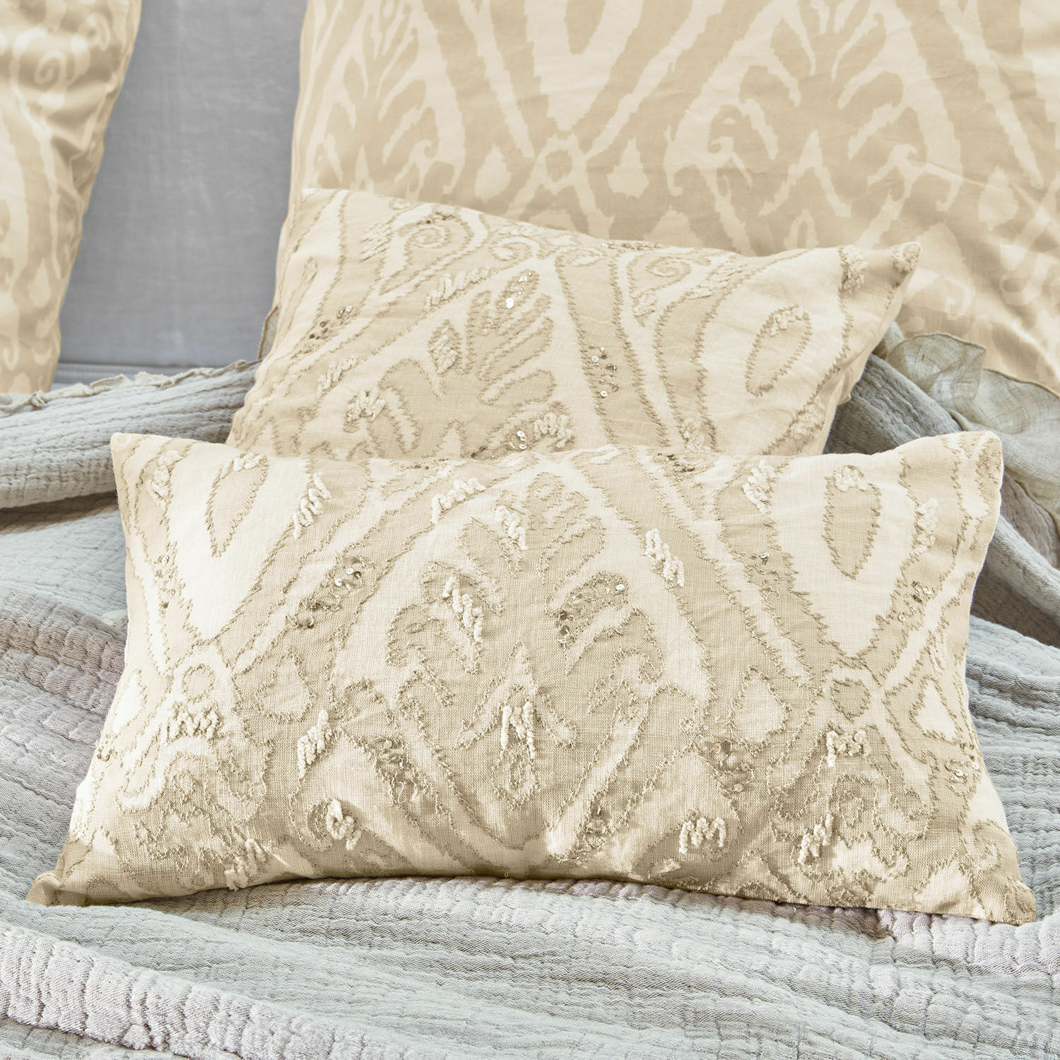 Cojín decorativo beige con bordado y lentejuelas en tela suave para sala de estar