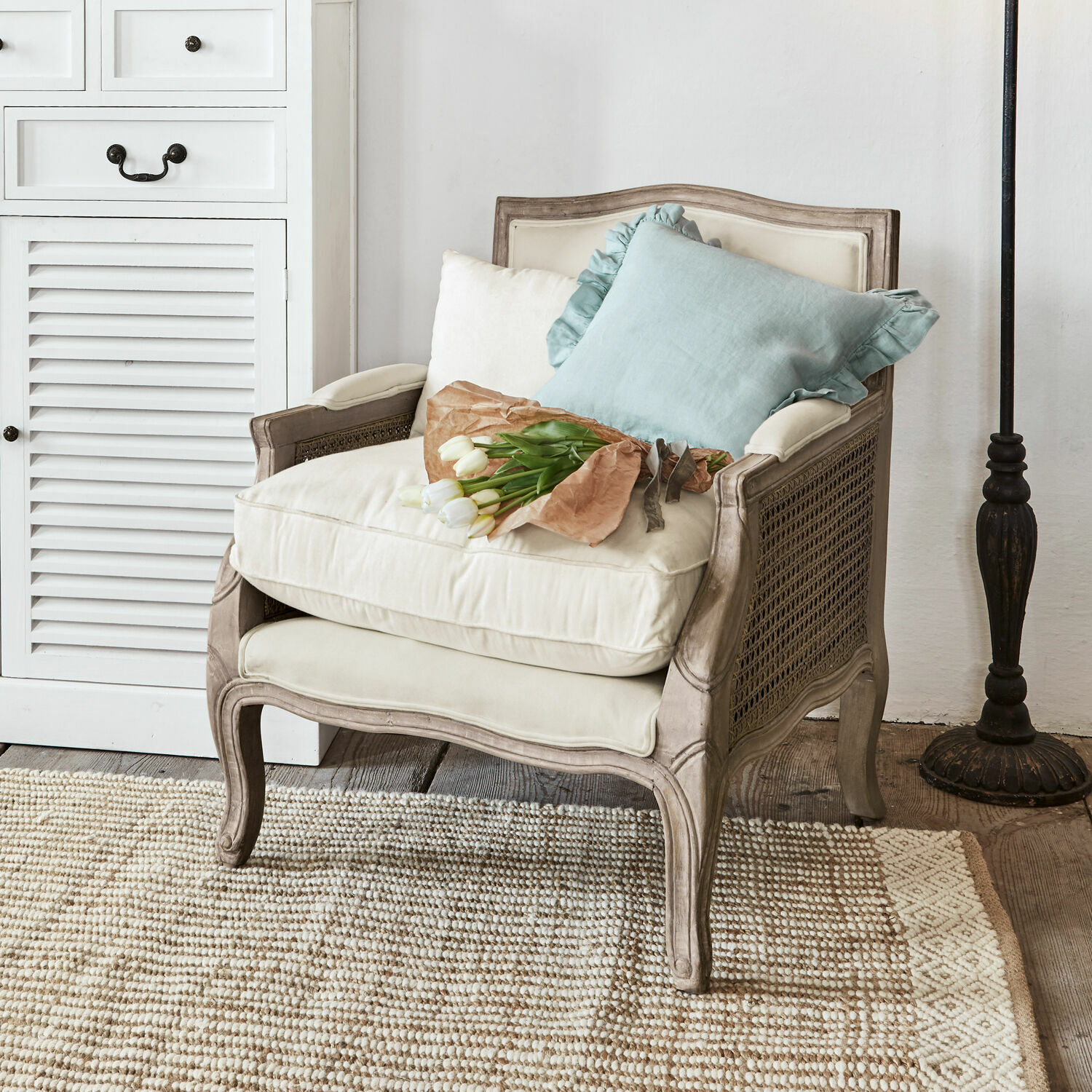 Sillón Alfort Sillón clásico de madera y tela crema con cojines y ramo de tulipanes blancos