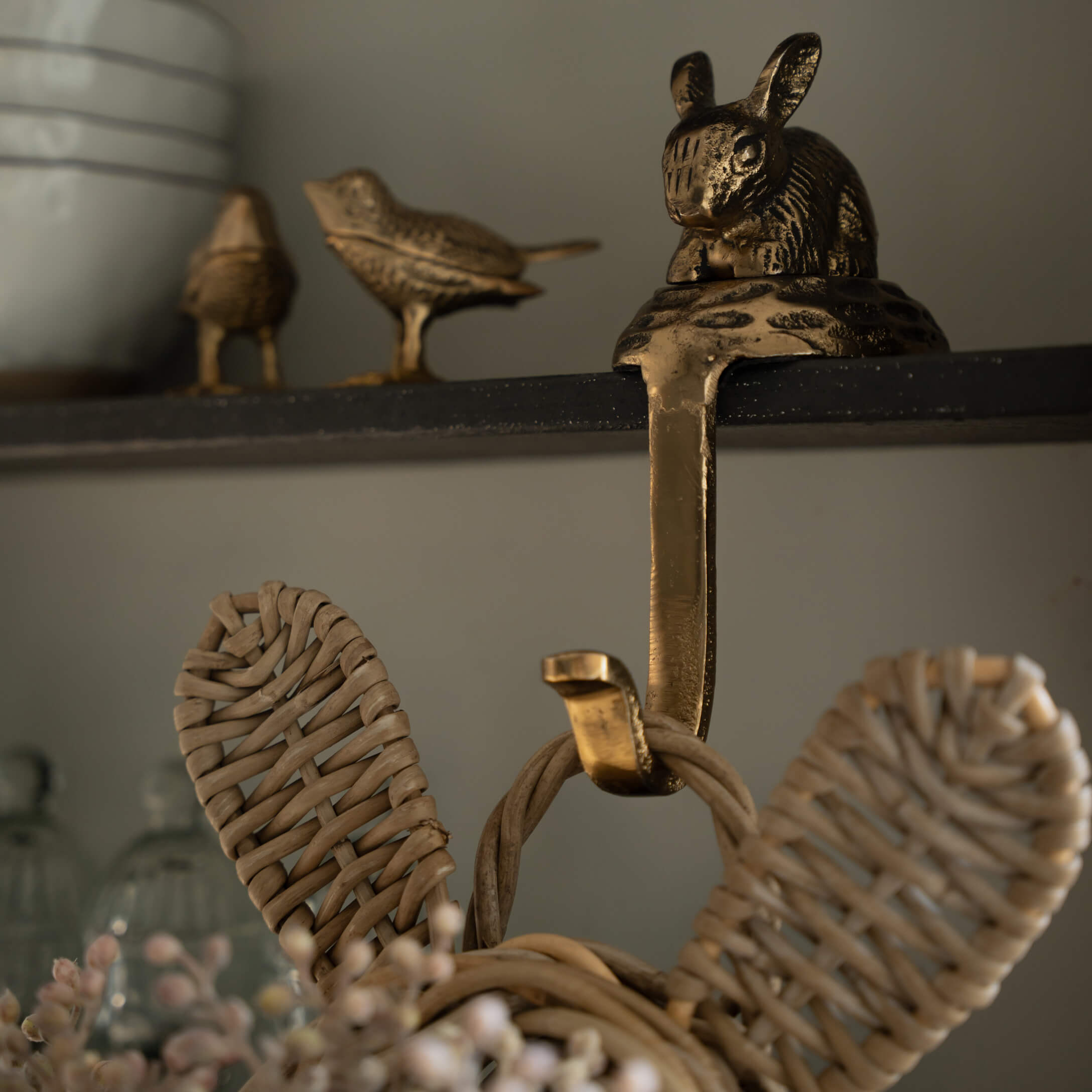 Percha de latón dorado con decoración de conejo y pájaros en estante negro para hogar