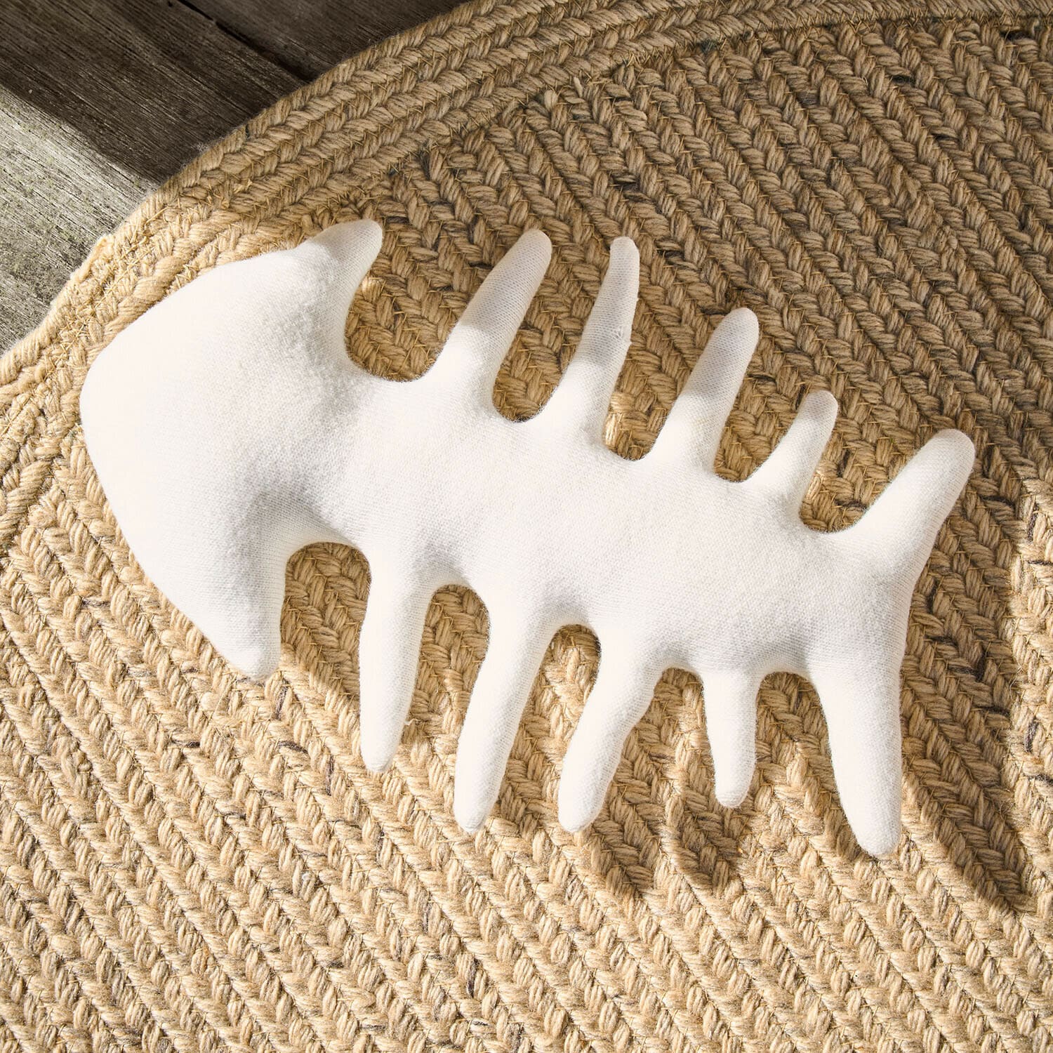 Decoración blanca en forma de esqueleto de pez de tela sobre alfombra trenzada de yute