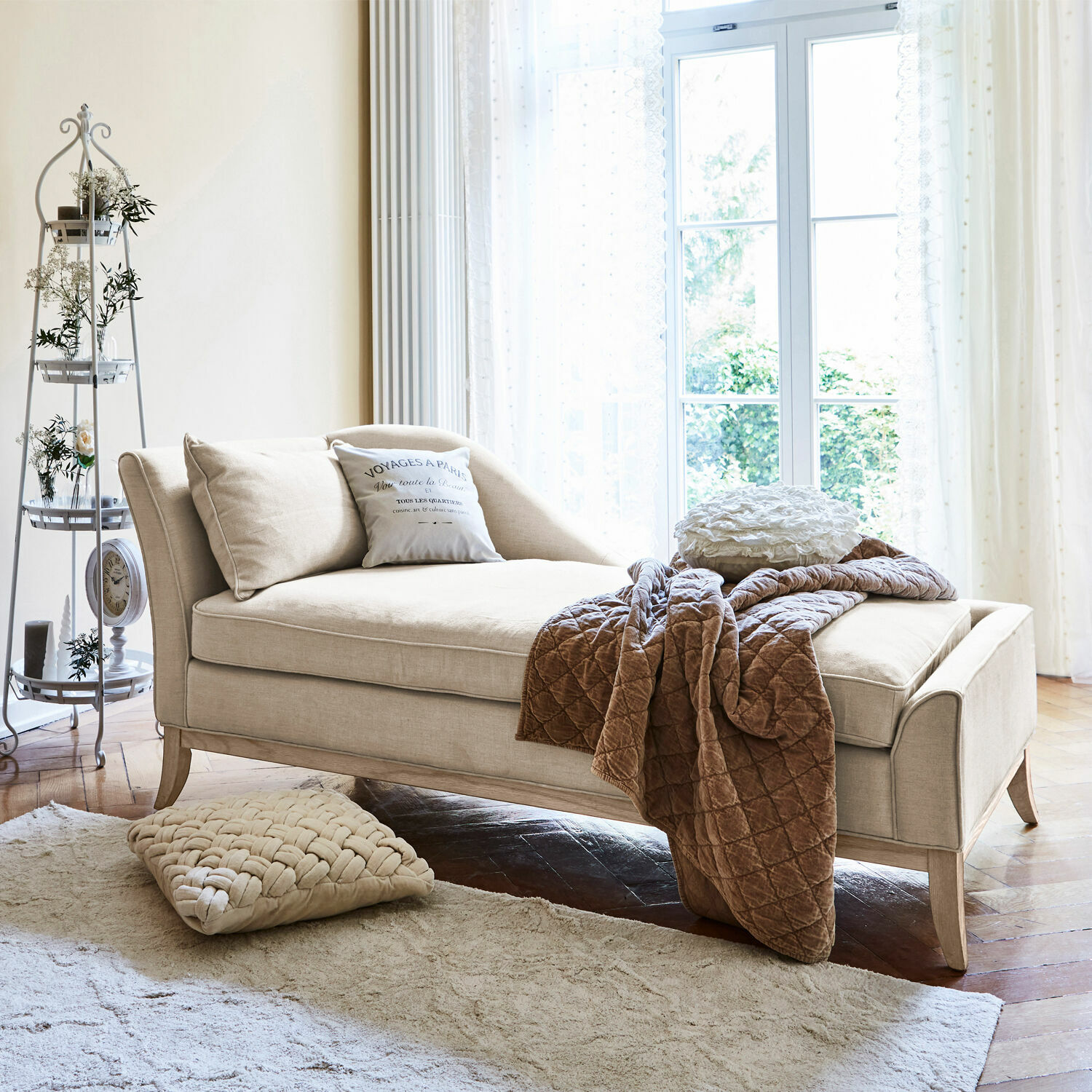Chaise longue Alphonse Chaise longue beige tapizada con cojines y manta marrón en sala luminosa