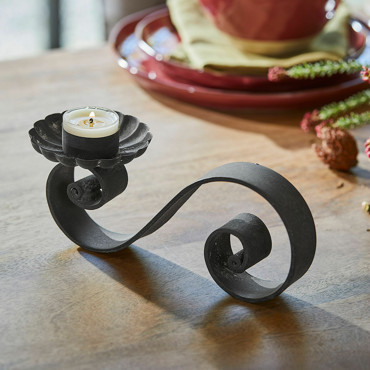 Set de 4 candeleros Vorelin Candelabro de metal negro con espiral decorativa y vela blanca sobre mesa de madera
