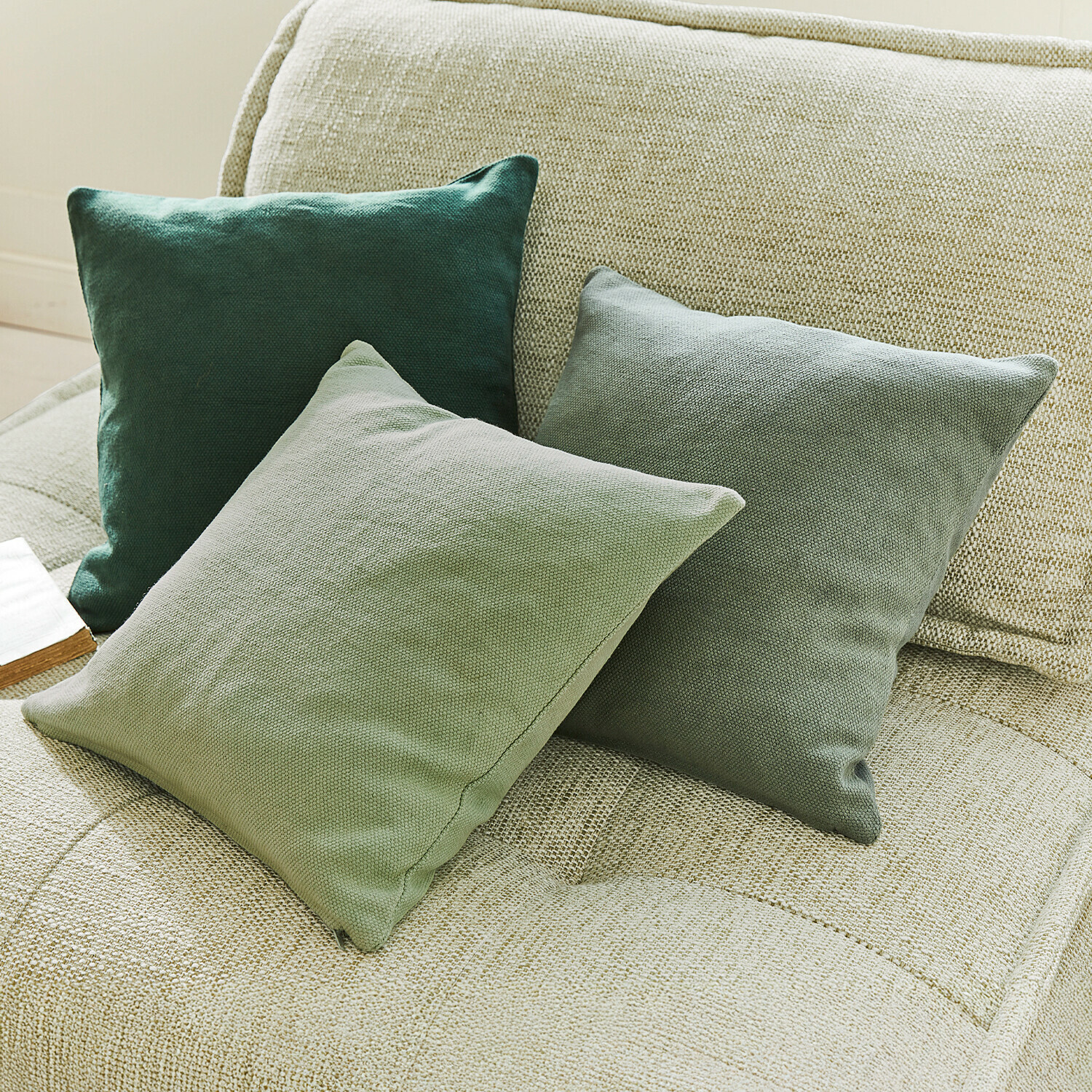 Set de 3 fundas de cojín Alienor Tres cojines decorativos verdes de tela sobre un sofá beige para sala de estar