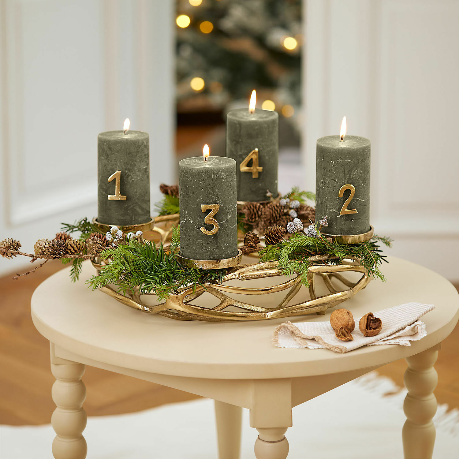Corona de velas Coldfield Corona de adviento verde con cuatro velas numeradas en dorado sobre mesa beige
