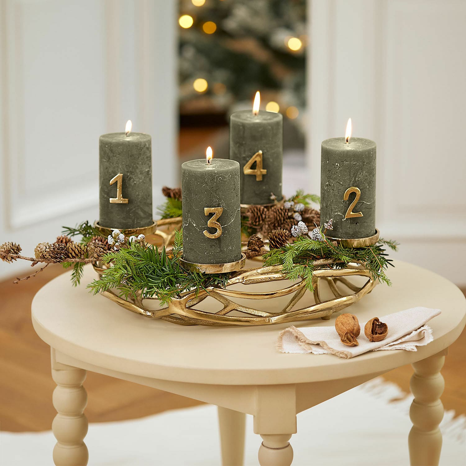 Corona de velas Coldfield Corona de adviento verde con cuatro velas numeradas en dorado sobre mesa beige