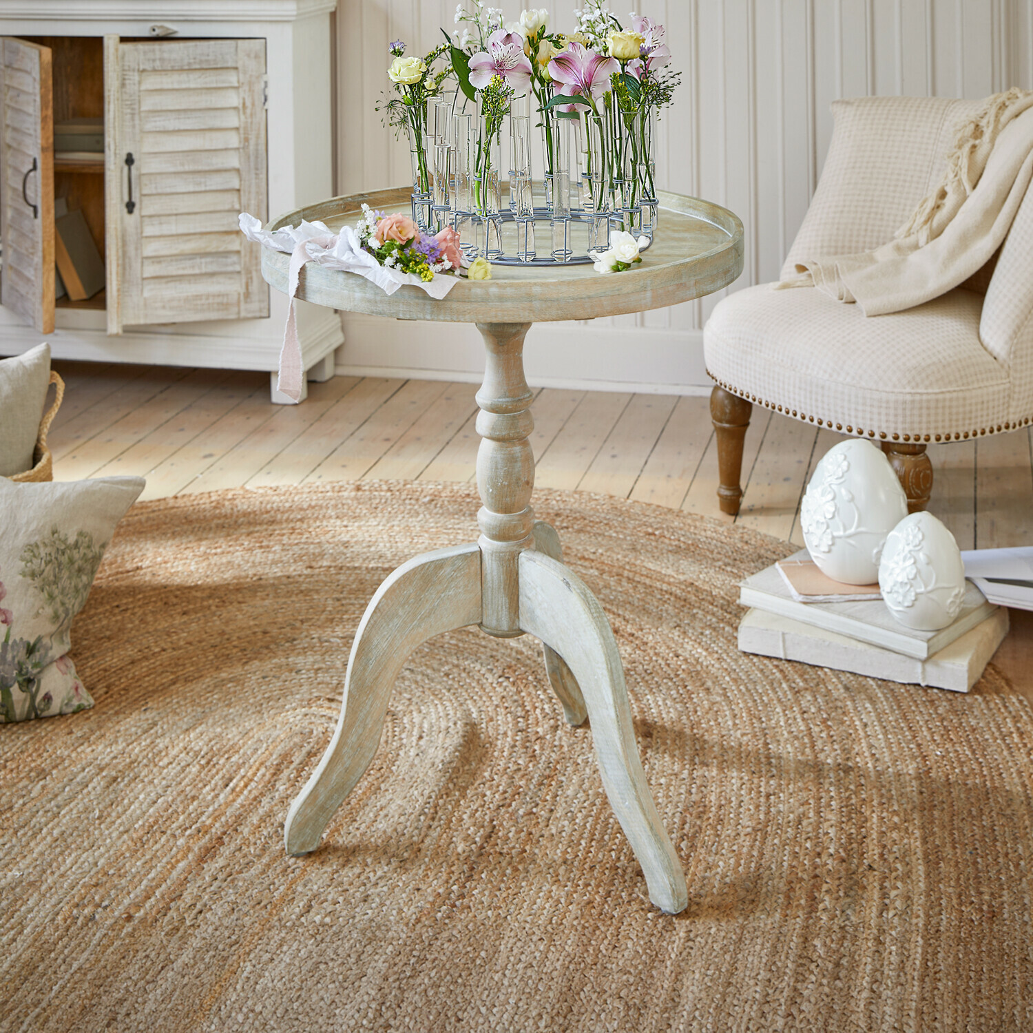 Mesa auxiliar Brookdale Mesa redonda de madera clara estilo vintage con decoración floral sobre la superficie en sala acogedora