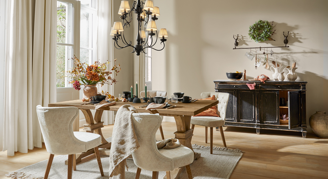 Comedor rústico con mesa de madera, sillas tapizadas crema y aparador negro envejecido