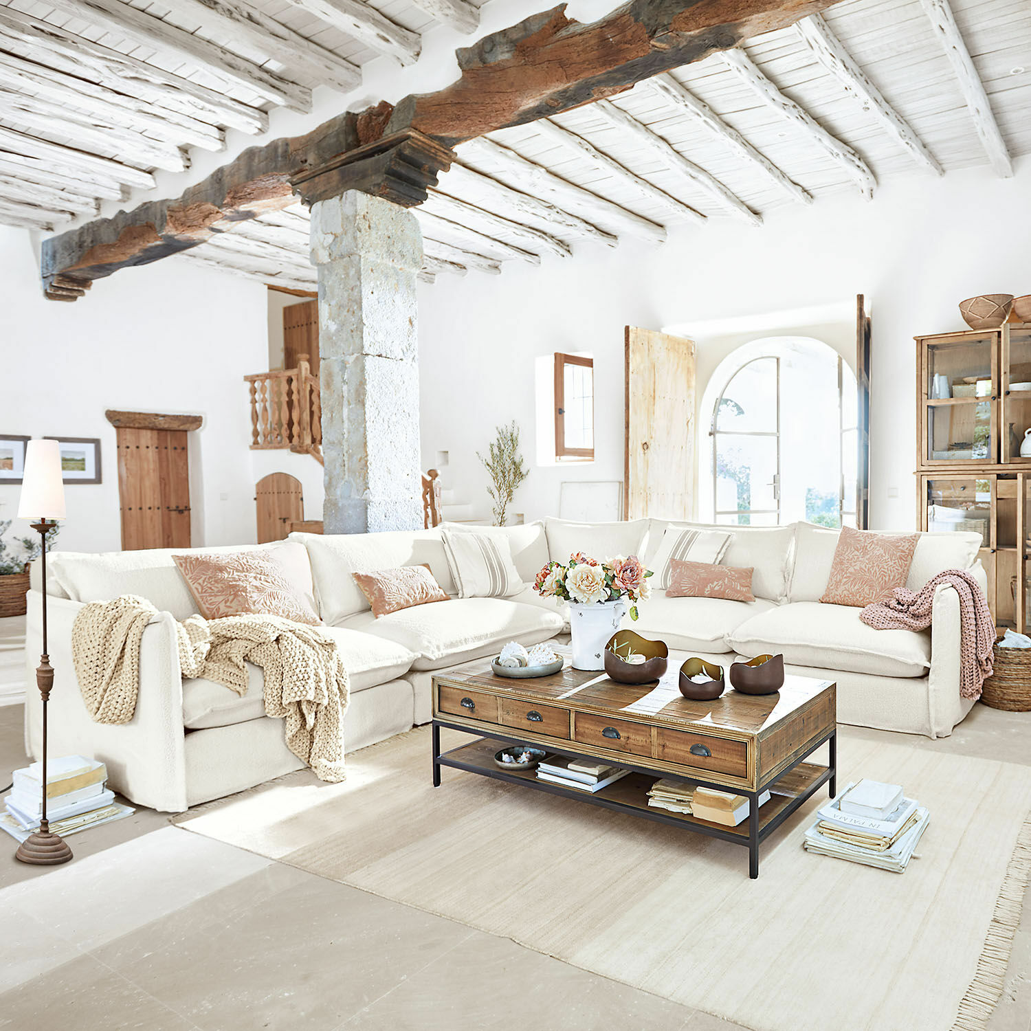 Sala amplia con sofá esquinero crema y mesa de centro de madera estilo rústico luminosa
