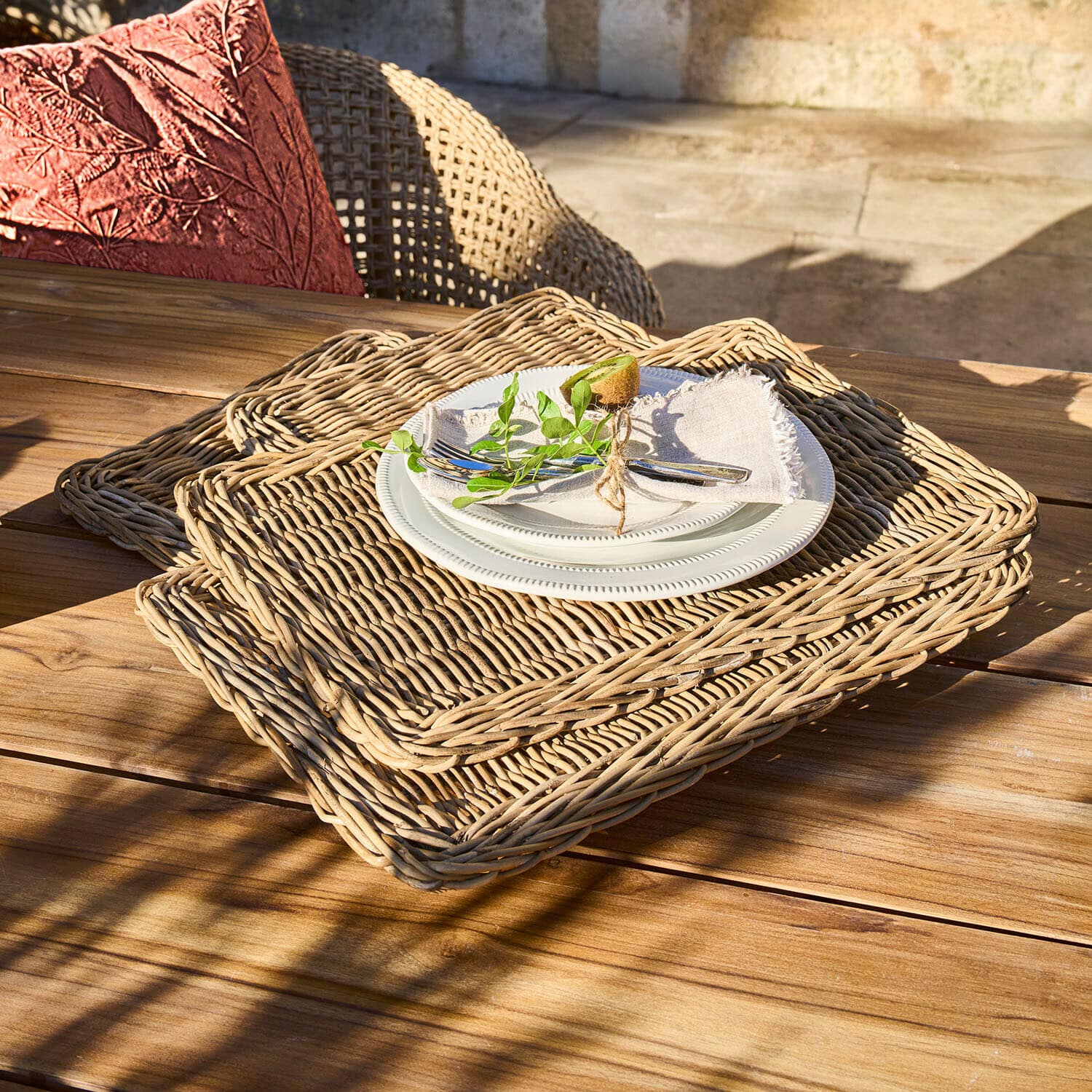 Juego de manteles individuales rectangulares de mimbre natural con plato blanco y cubiertos sobre mesa de madera