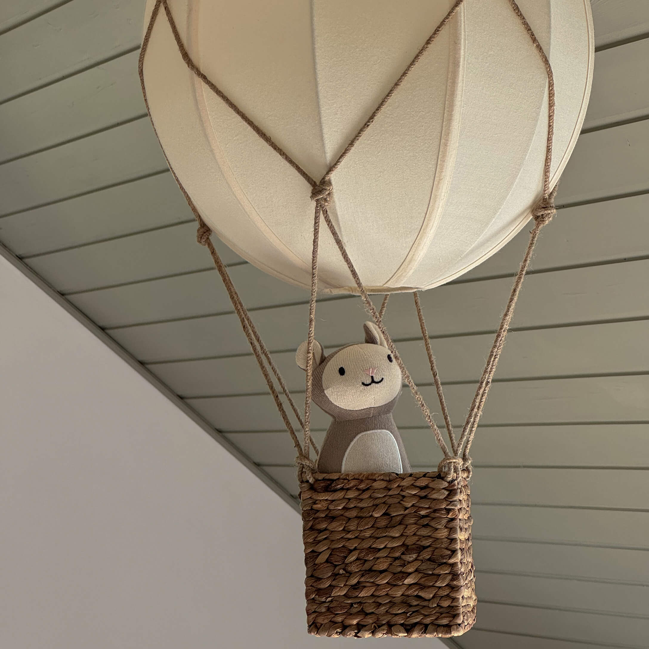 Globo decorativo colgante con cesta de mimbre y peluche beige en tonos neutros