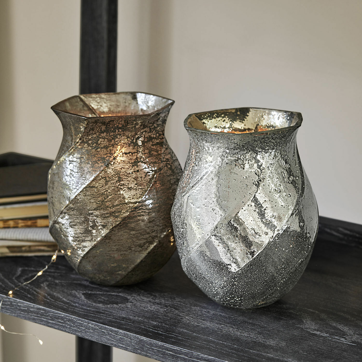 Set de 2 portavelas Tixovel Dos jarrones decorativos de vidrio en plata y oro con textura sobre una estantería oscura
