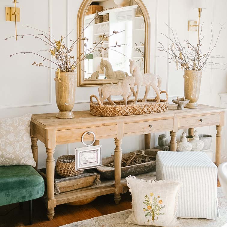 Mesa de madera con decoración rústica y espejo en un interior luminoso y acogedor