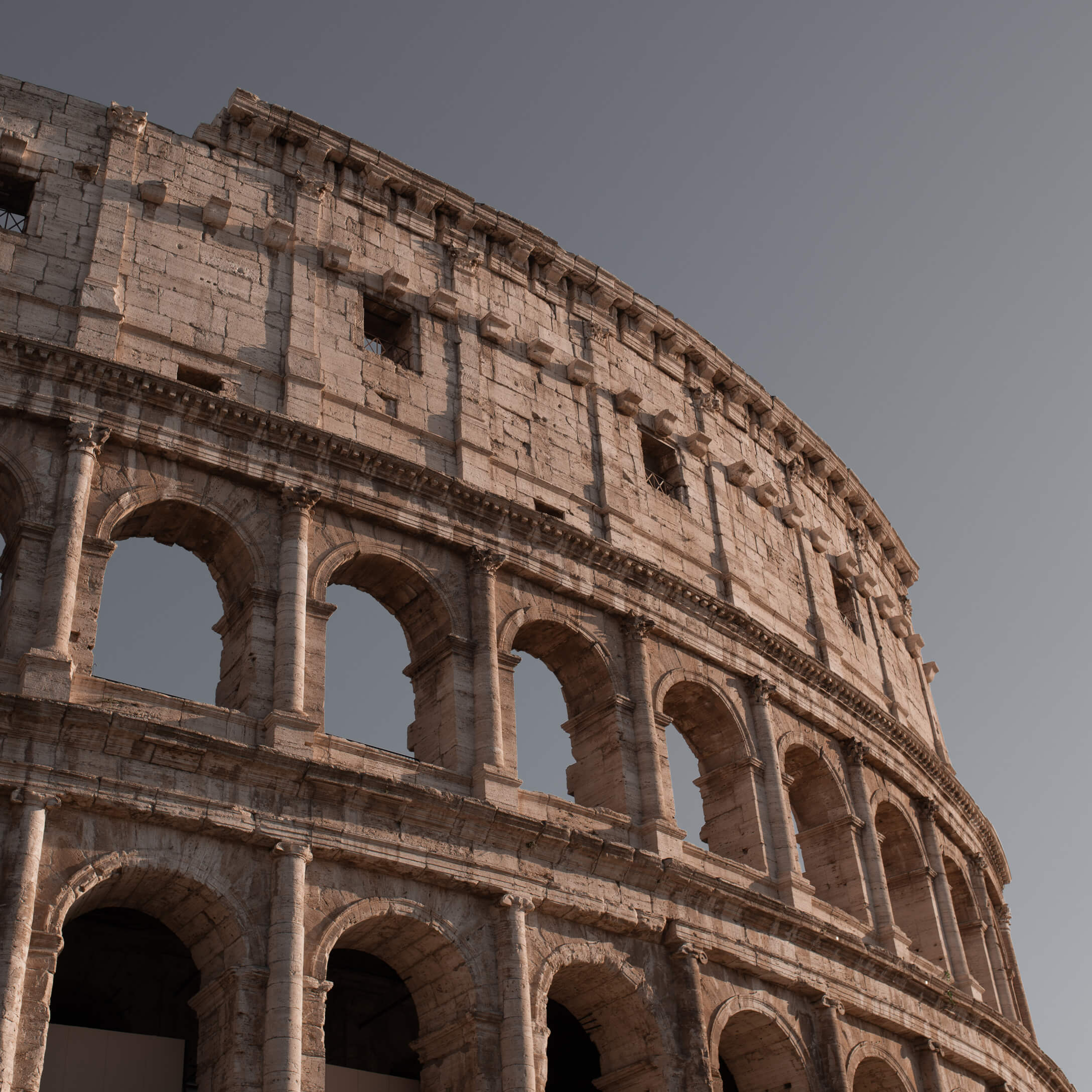 Detalle del Coliseo romano antiguo de piedra cálida bajo un cielo azul claro
