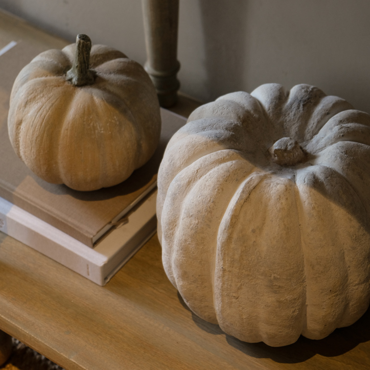 Calabazas decorativas de hormigón en tonos naturales sobre mesa de madera, decoración otoñal interior