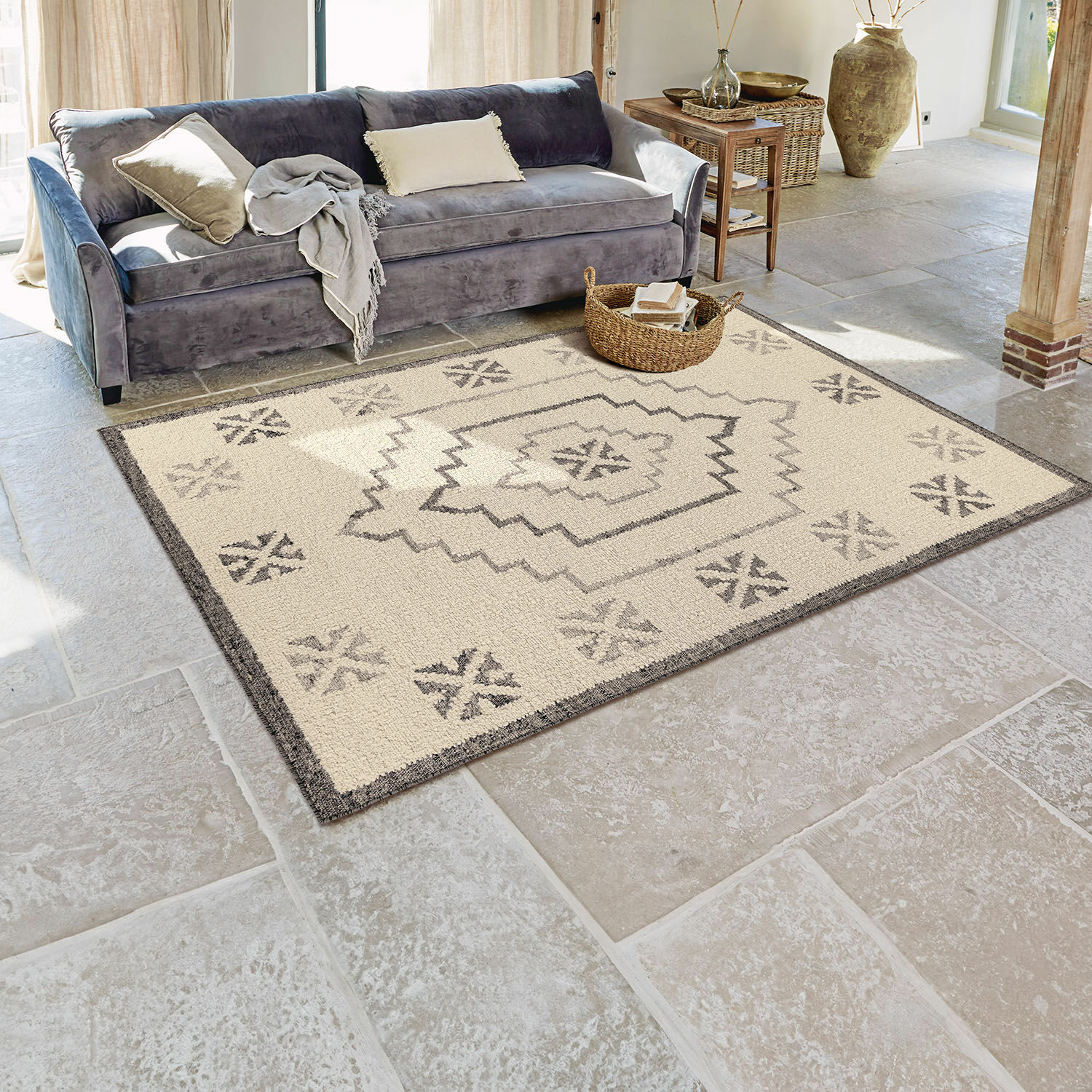 Alfombra Xerven Alfombra beige con diseño geométrico gris sobre suelo de piedra en sala de estar