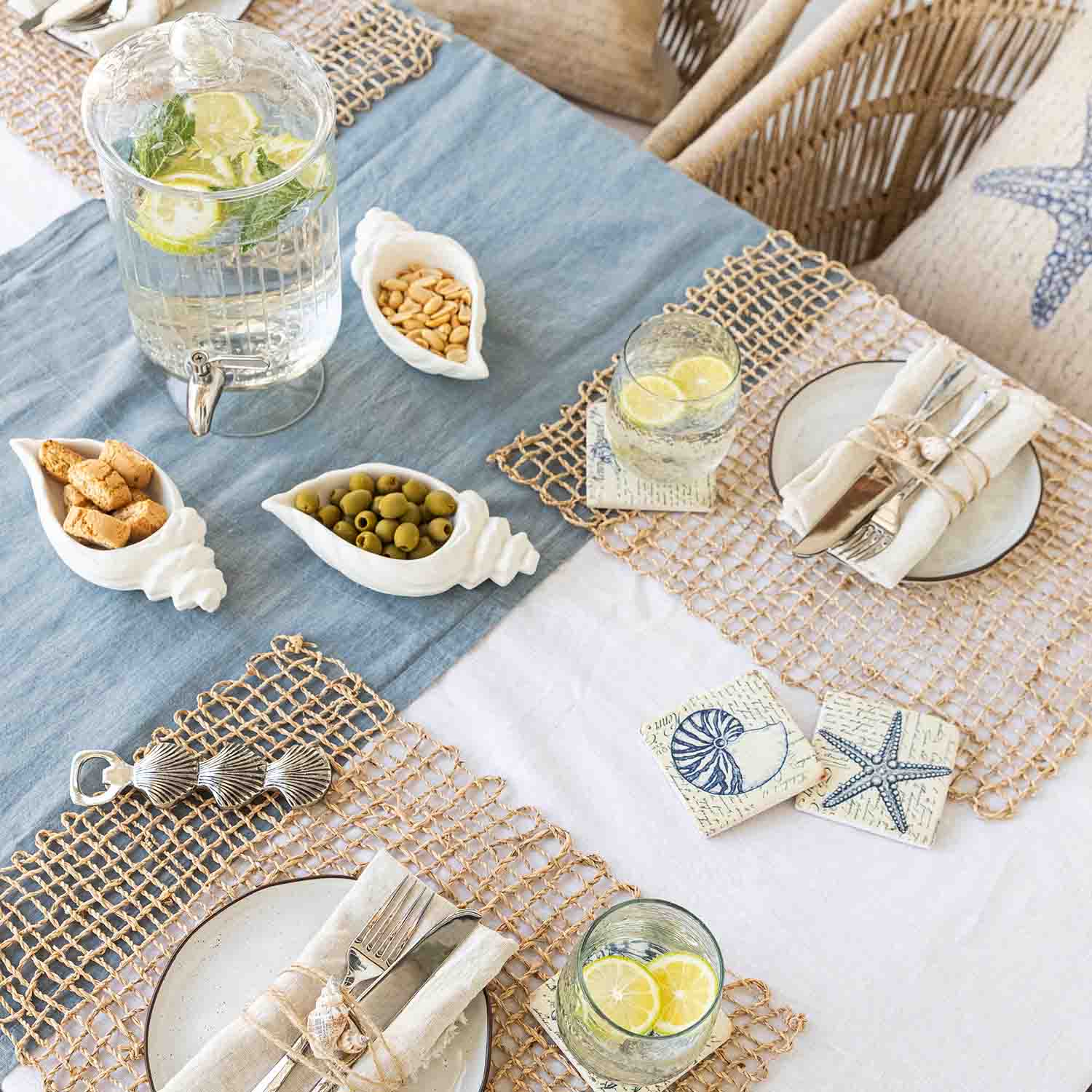 Mesa veraniega con decoración marina, cuencos de cerámica blanca en forma de concha con aperitivos y limonada