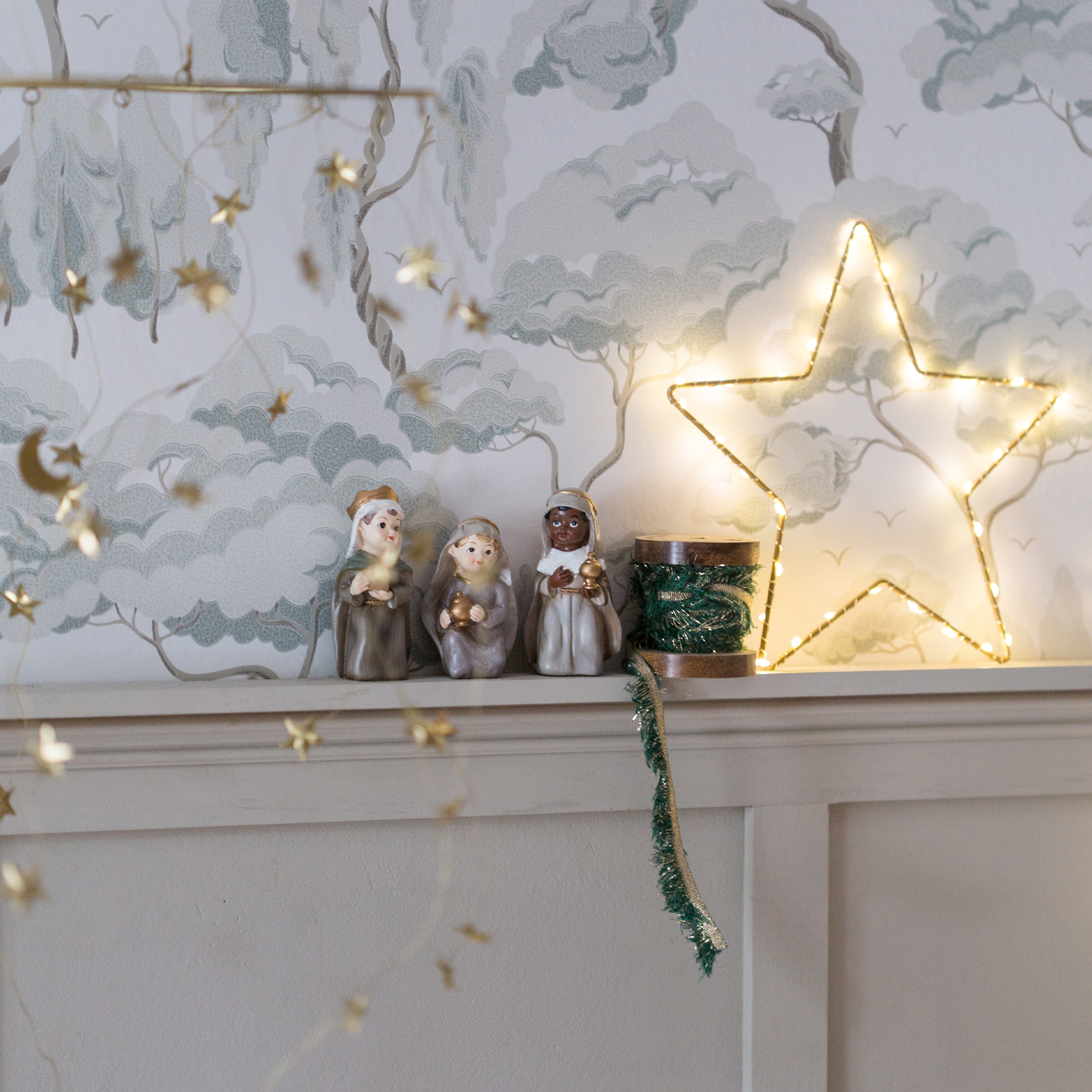 Decoración navideña con tres figuras de los Reyes Magos y estrella luminosa en estante blanco