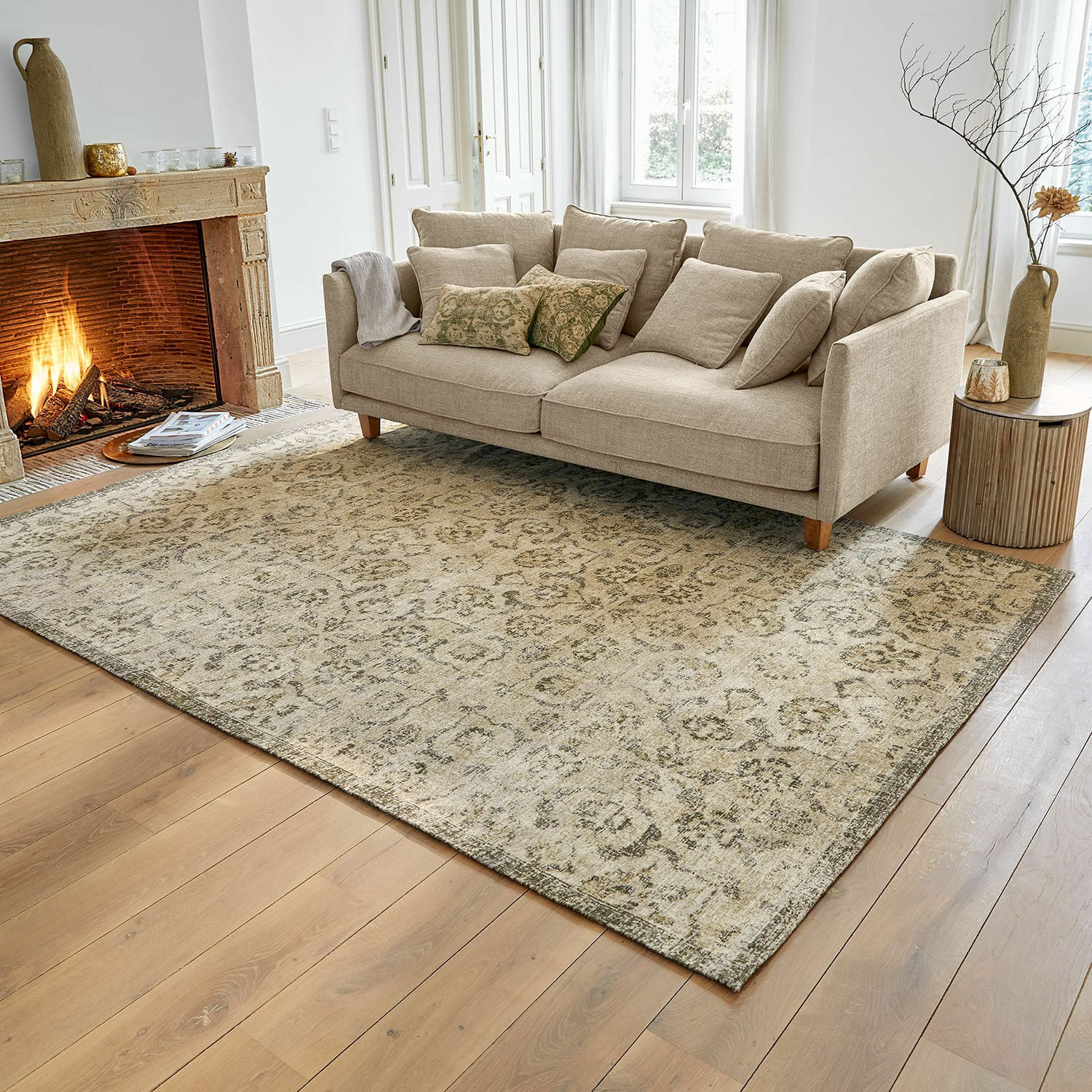 Alfombra beige con patrón sutil sobre suelo de madera en sala con sofá beige y chimenea