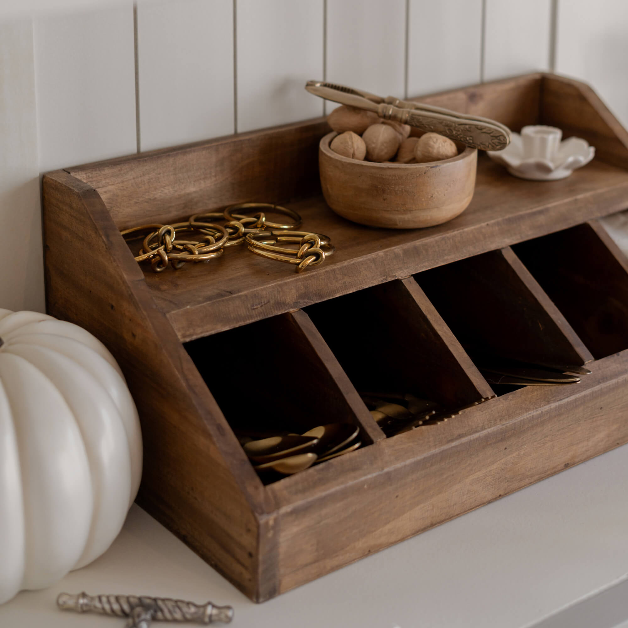 Organizador de madera con compartimentos y cuenco con nueces sobre superficie clara para guardar objetos pequeños