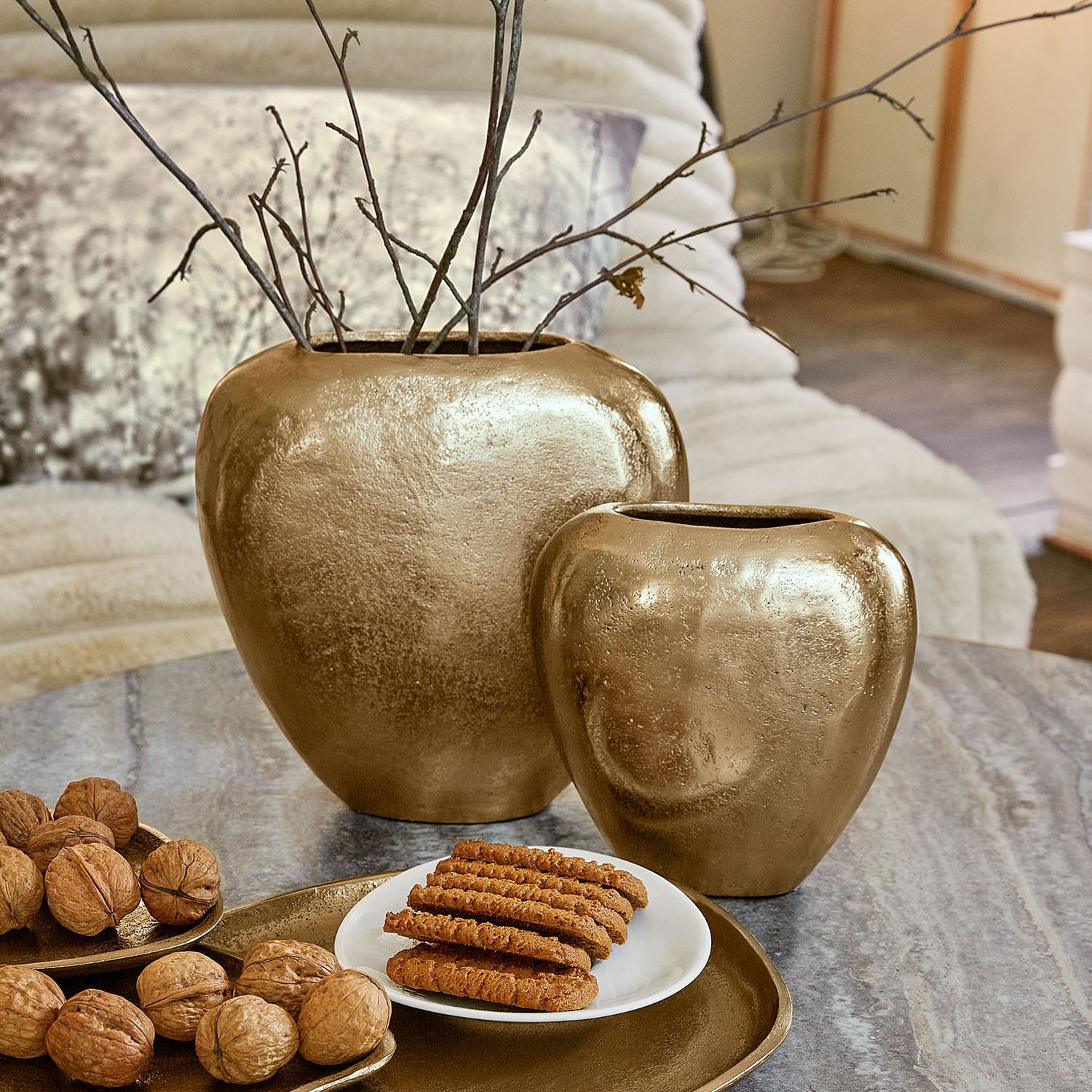 Conjunto de dos jarrones de cerámica dorada sobre mesa con nueces y galletas, decoración interior