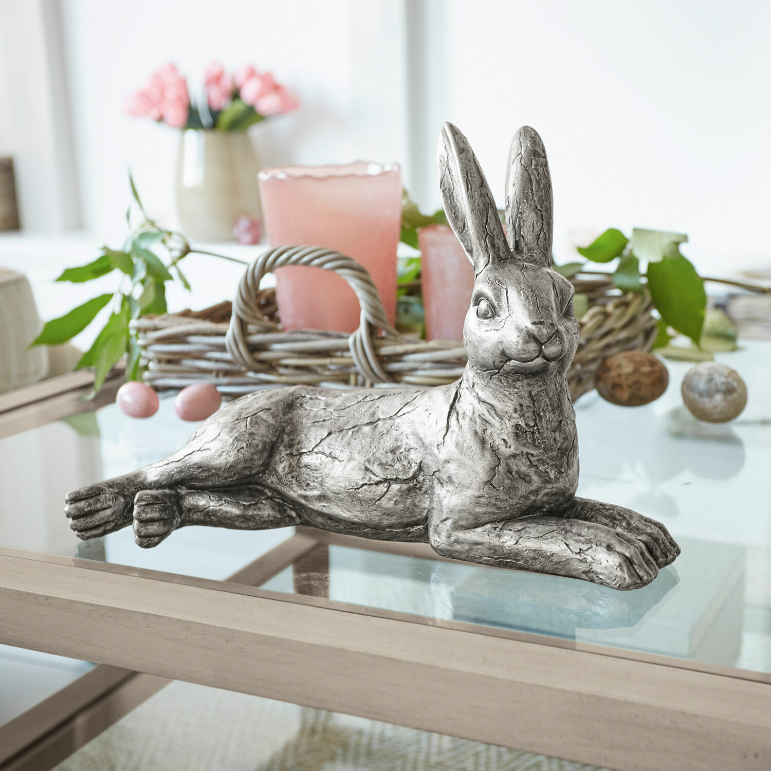 Conejo Fiorentin Conejo decorativo de metal plateado sobre mesa de cristal con decoración primaveral