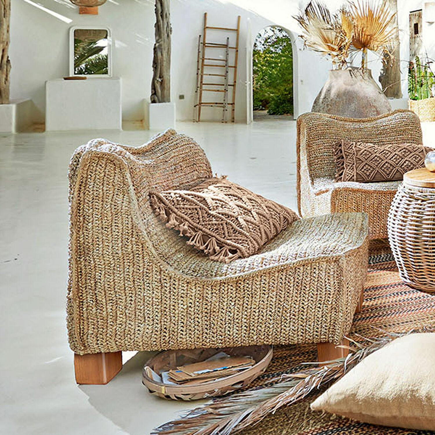 Sillón de ratán trenzado en color natural con cojín decorativo y patas de madera clara