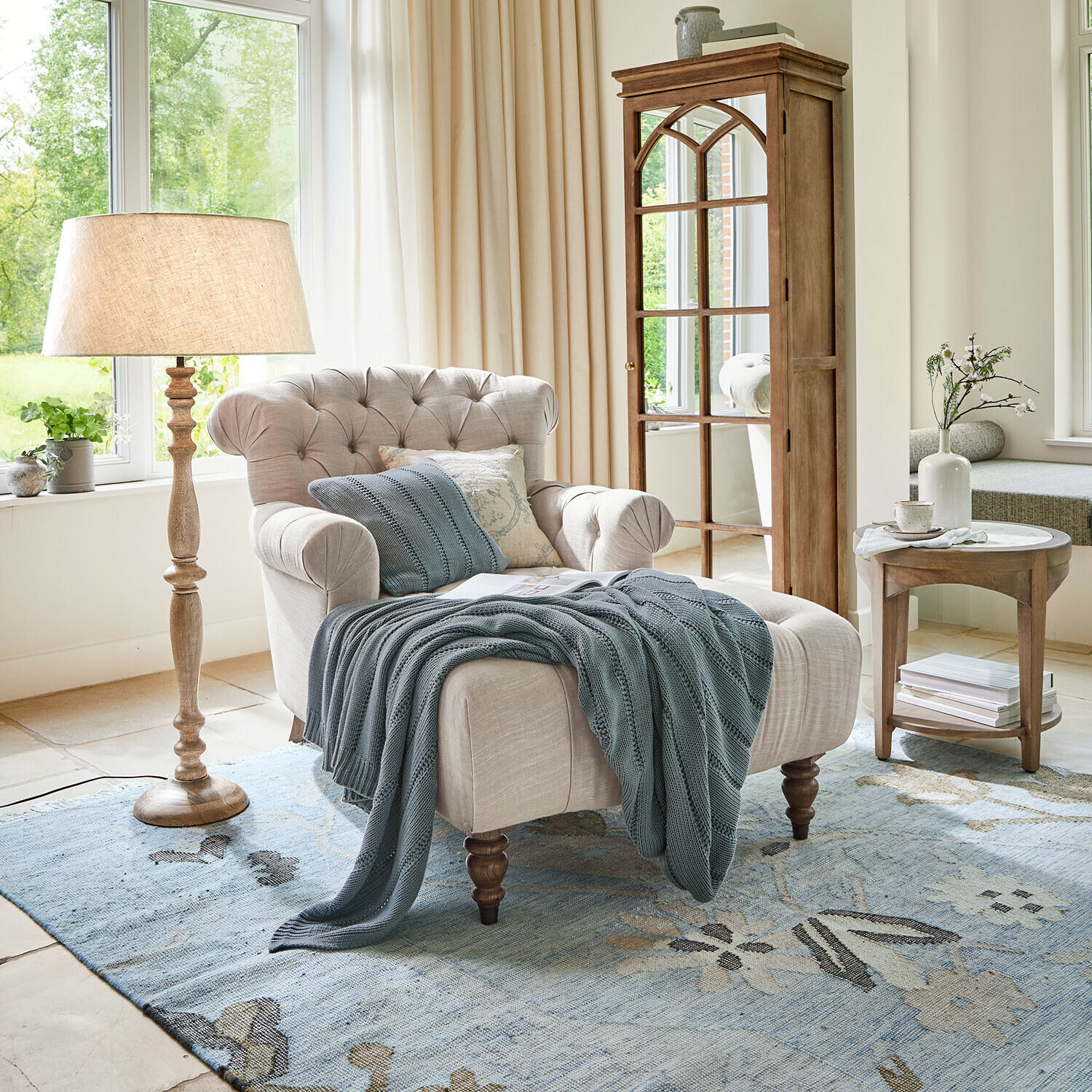 Chaise longue Springfield Village Sillón beige de tela con respaldo capitoné y manta azul sobre alfombra azul en sala luminosa