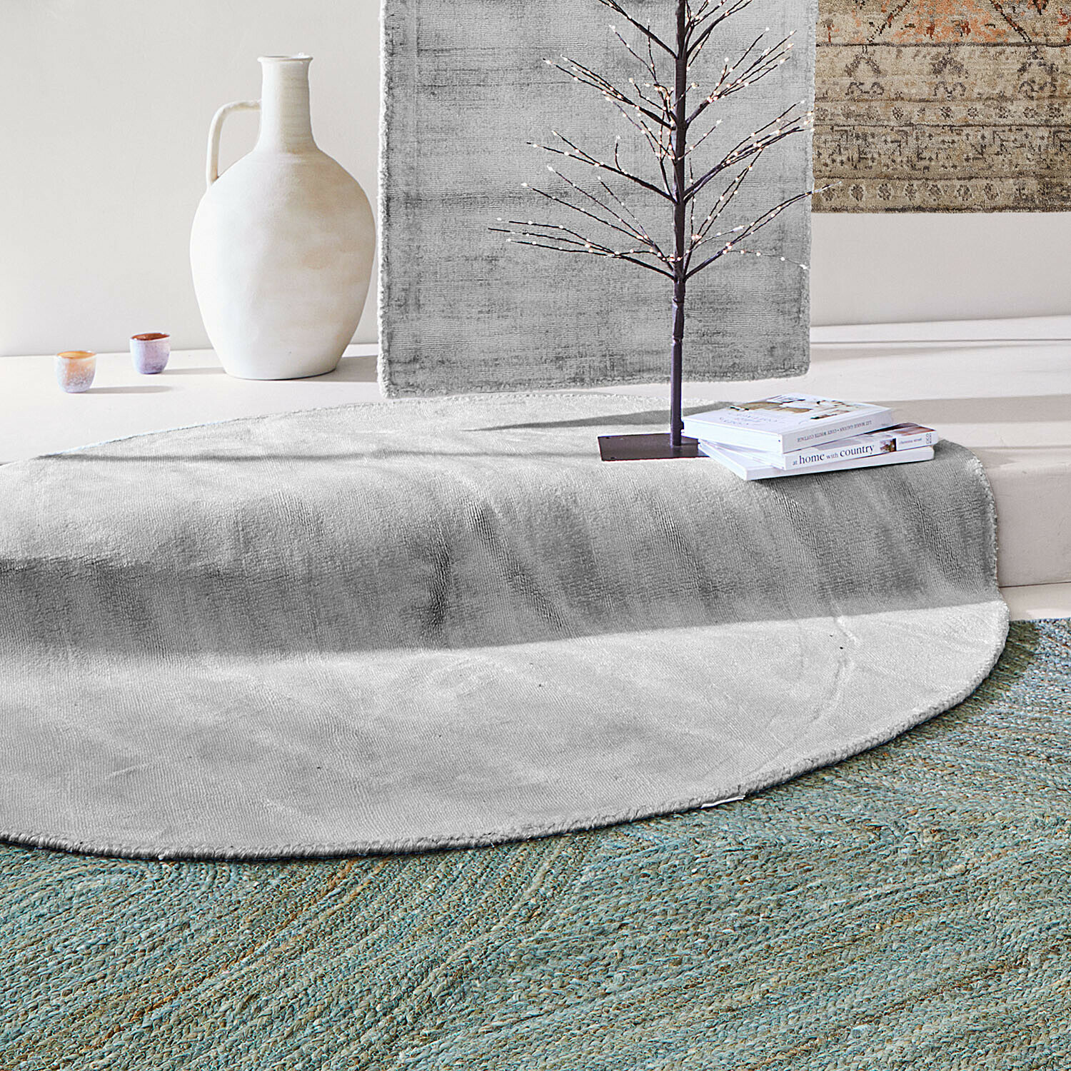 Alfombra Mariselle Alfombra redonda gris de material suave con jarrón decorativo y libros en un interior moderno