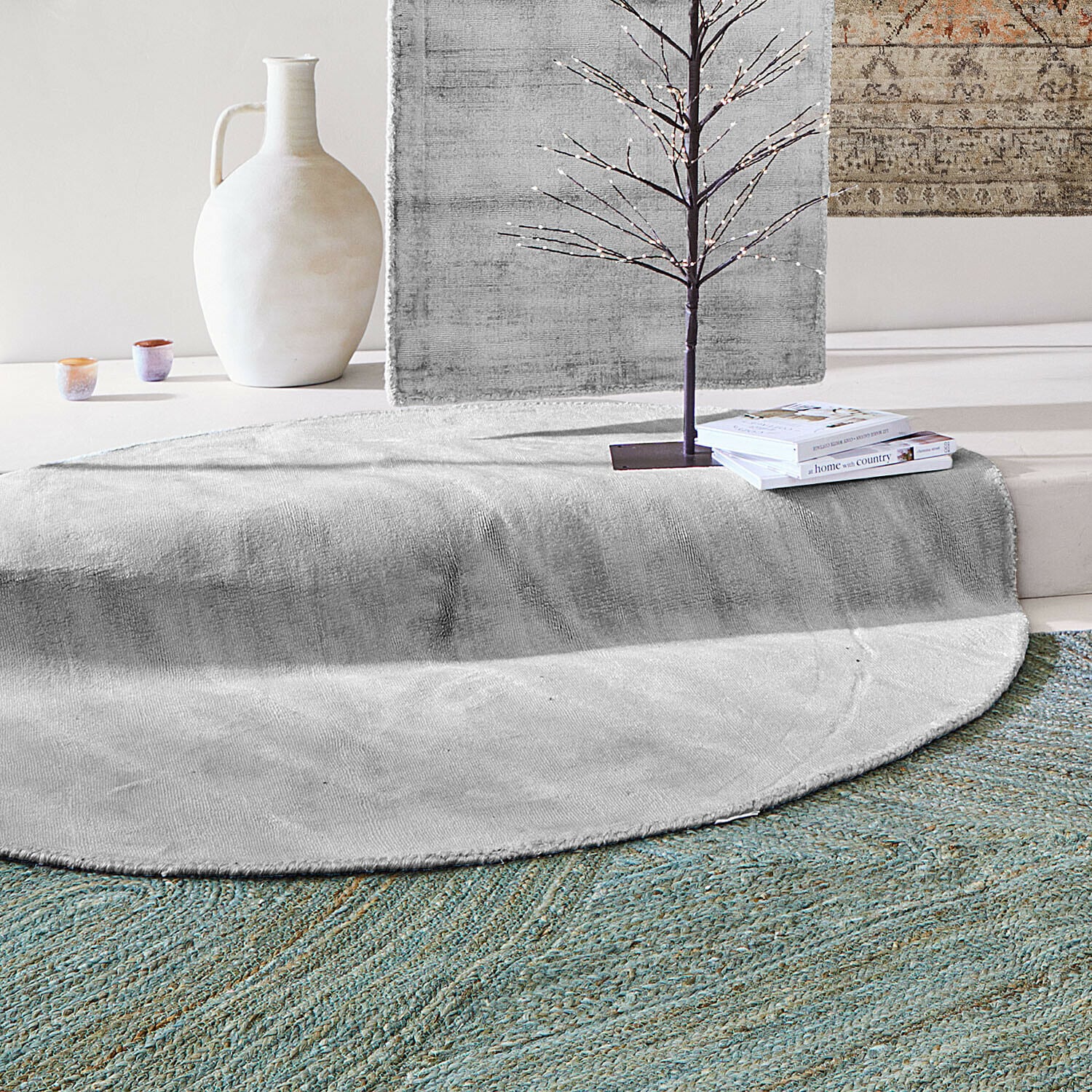 Alfombra Mariselle Alfombra redonda gris de material suave con jarrón decorativo y libros en un interior moderno