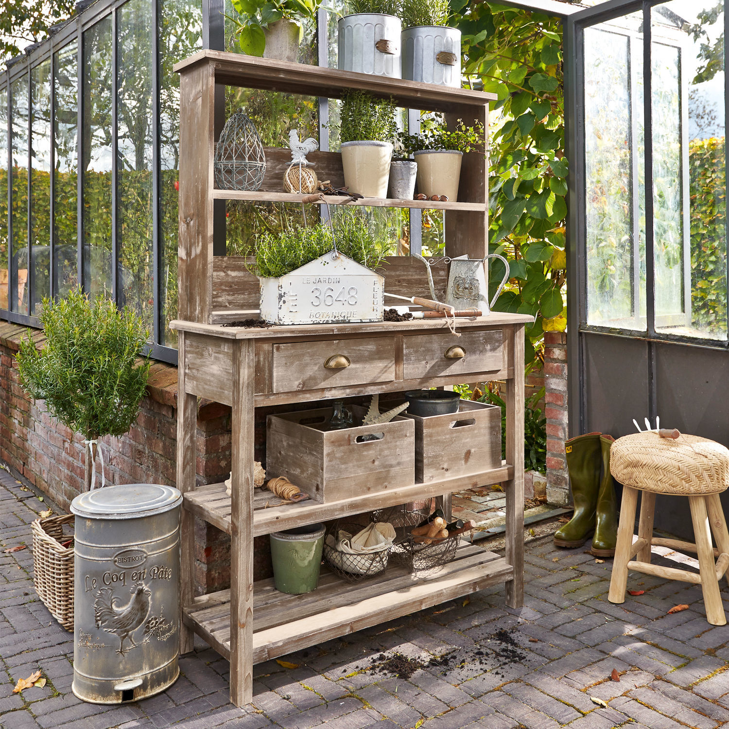 Mesa de jardinería Landover Mesa de jardín de madera con estantes, macetas, herramientas de jardinería y plantas verdes en un invernadero