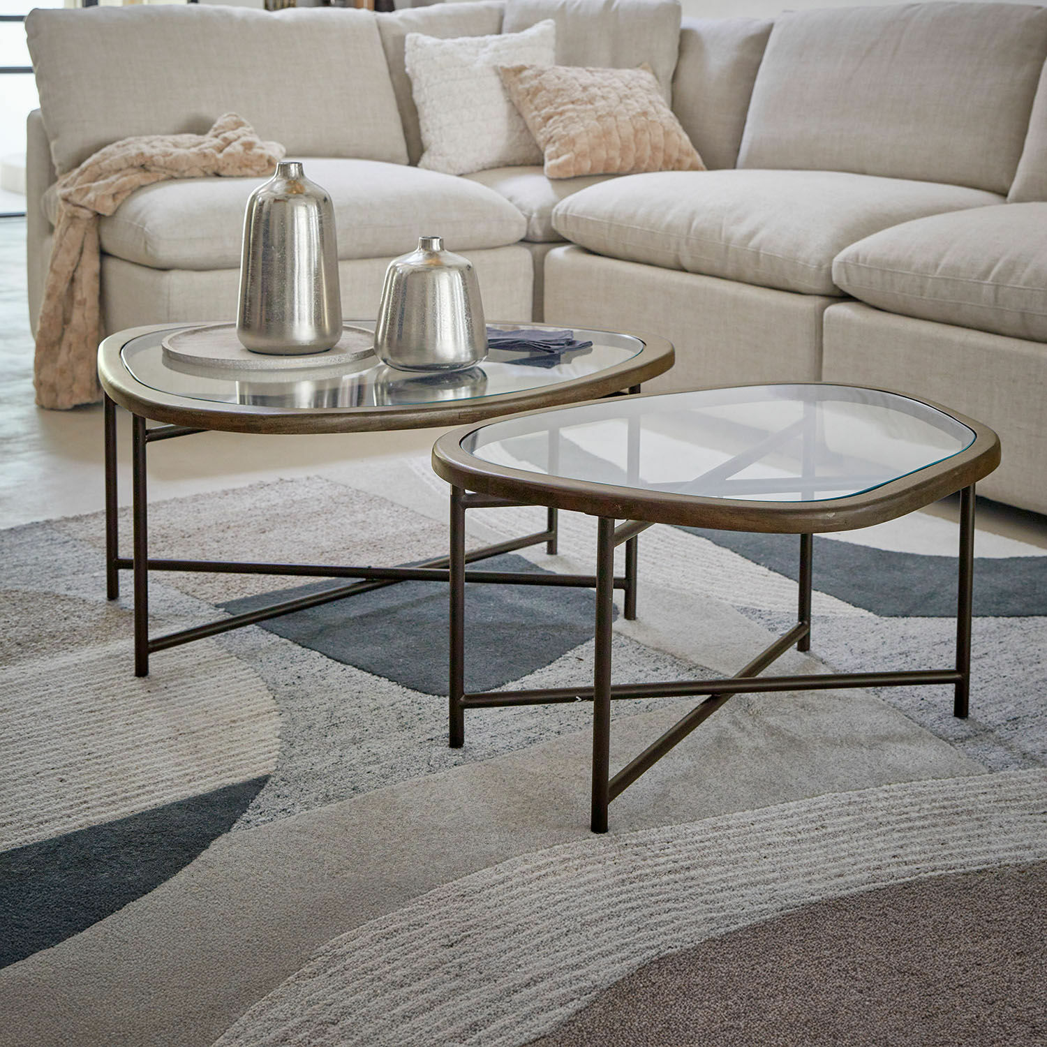 Set de 2 mesas de centro Kembria Conjunto de dos mesas de centro con estructura metálica y tapa de cristal en salón con sofá beige