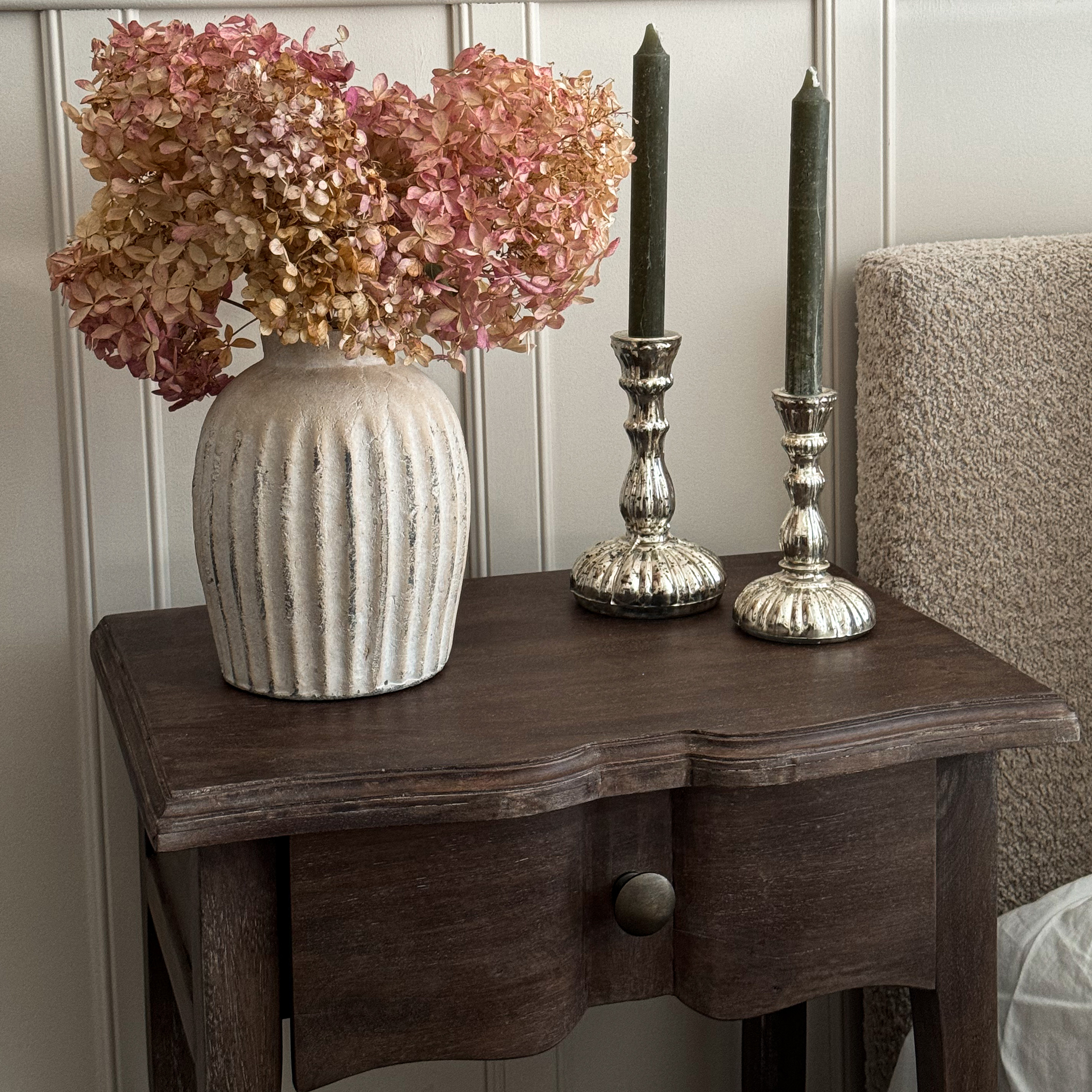 Jarrón de cerámica beige con flores secas rosas sobre mesa de madera oscura para decoración