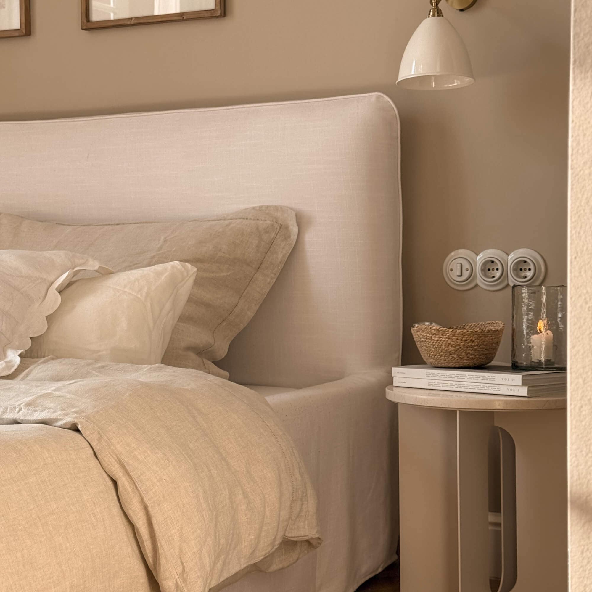 Dormitorio acogedor con cama tapizada beige y ropa de cama de lino natural