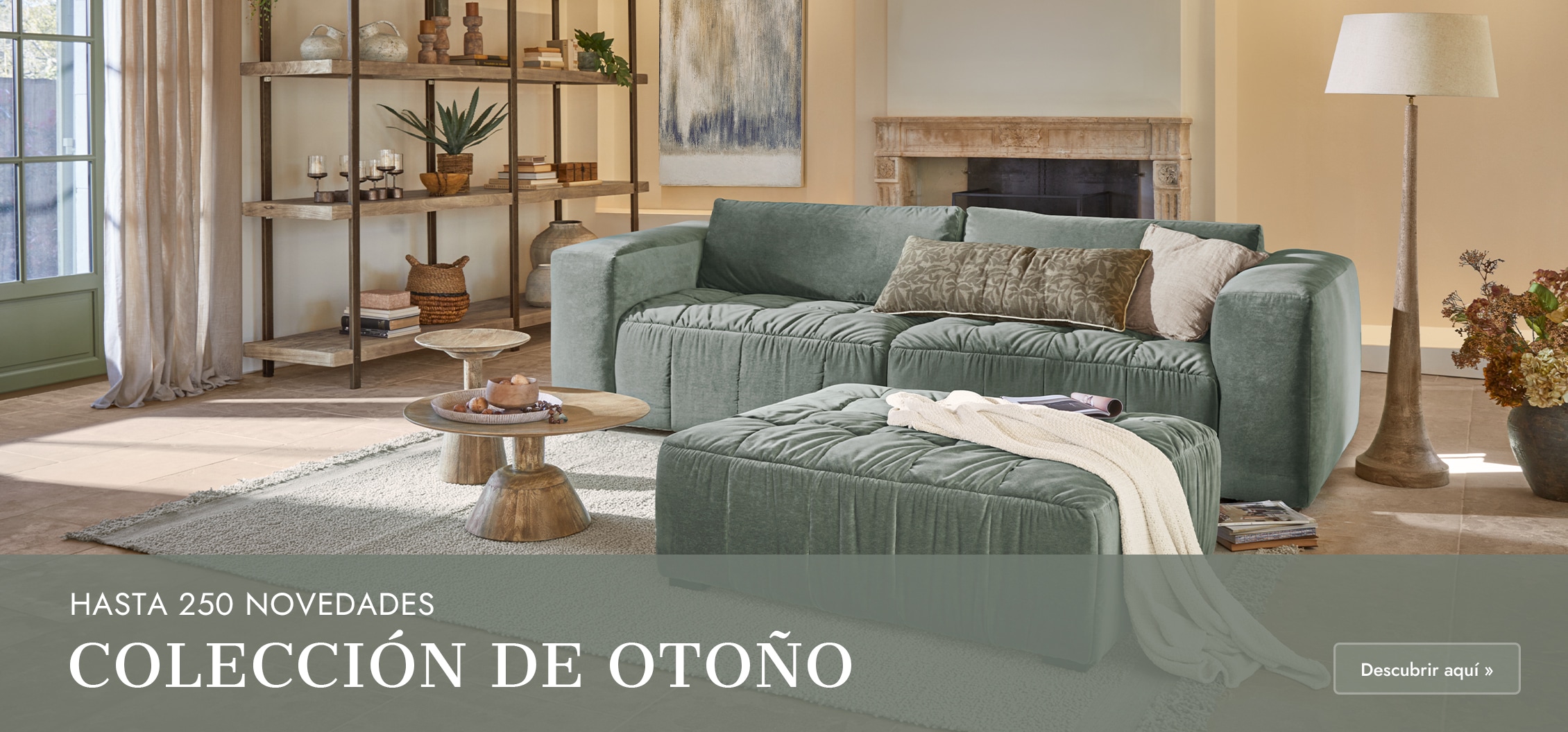 Sofá esquinero verde de terciopelo con cojines y mesas de madera en salón luminoso con chimenea
