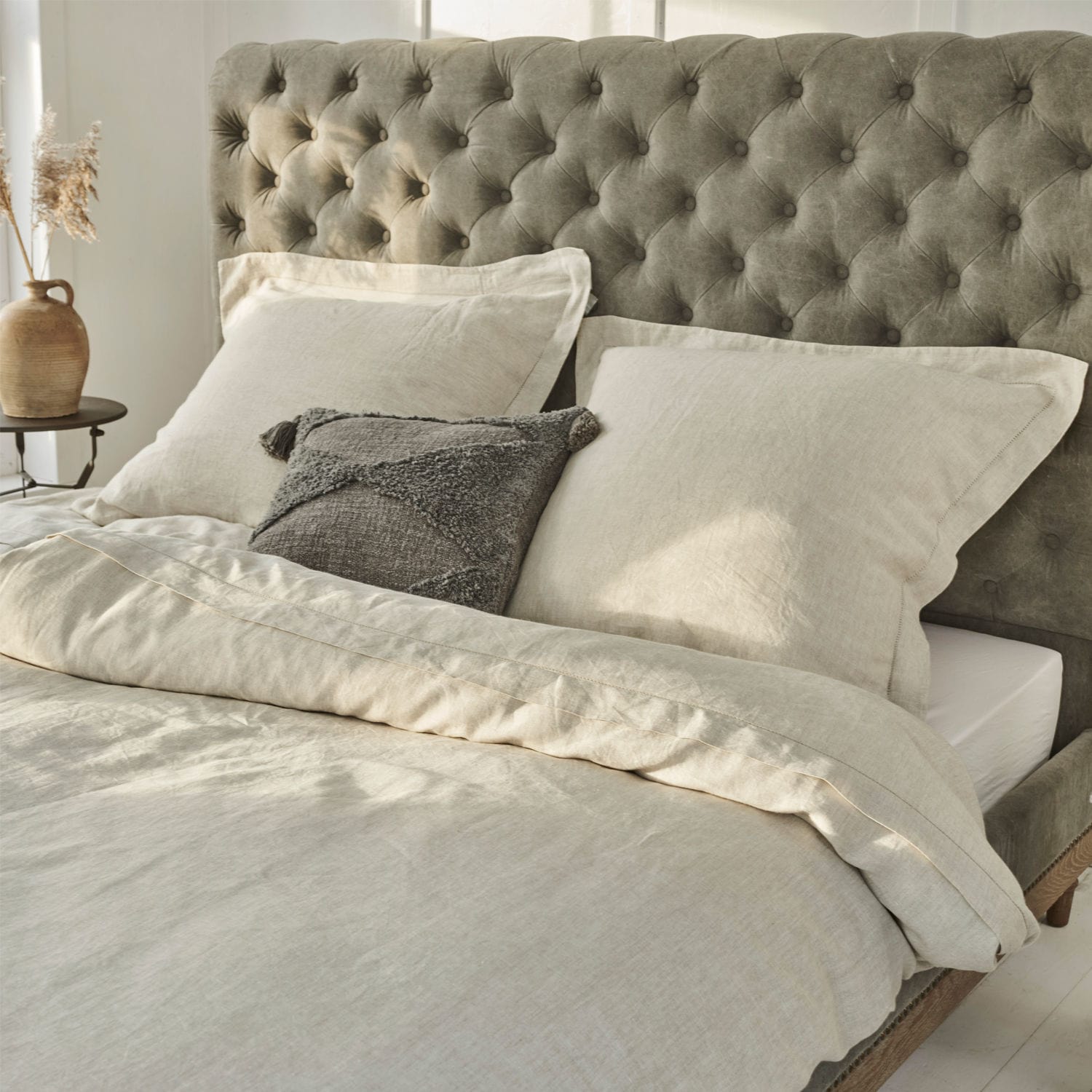 Ropa de cama Kilanema Ropa de cama beige de lino en cama con cabecero gris capitoné, cojín decorativo gris