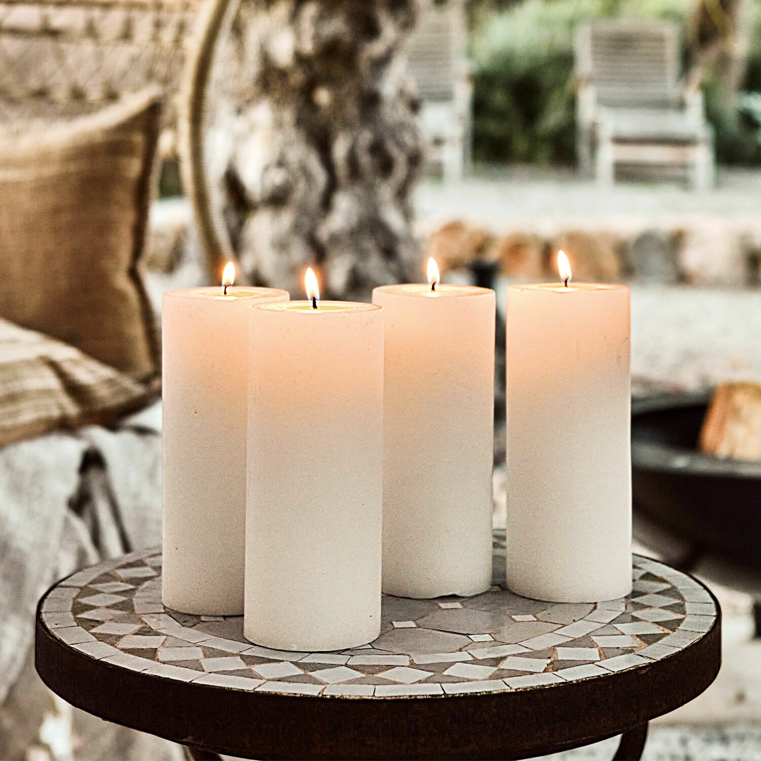 Cuatro velas blancas sobre mesa de mosaico, decoración interior y luz ambiental