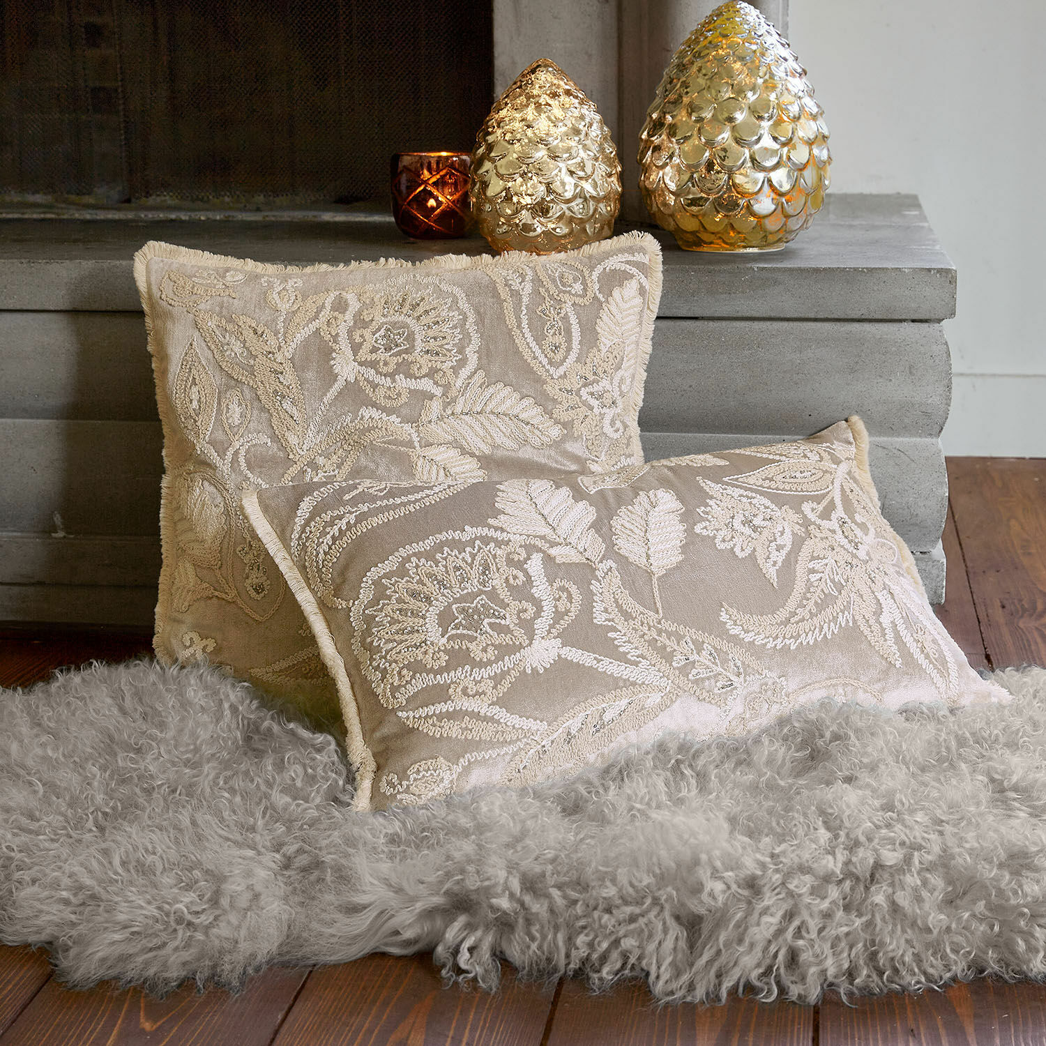 Set de 2 fundas de cojín Oplevine Cojines decorativos beige bordados sobre alfombra gris de piel sintética junto a la chimenea, textiles para el hogar